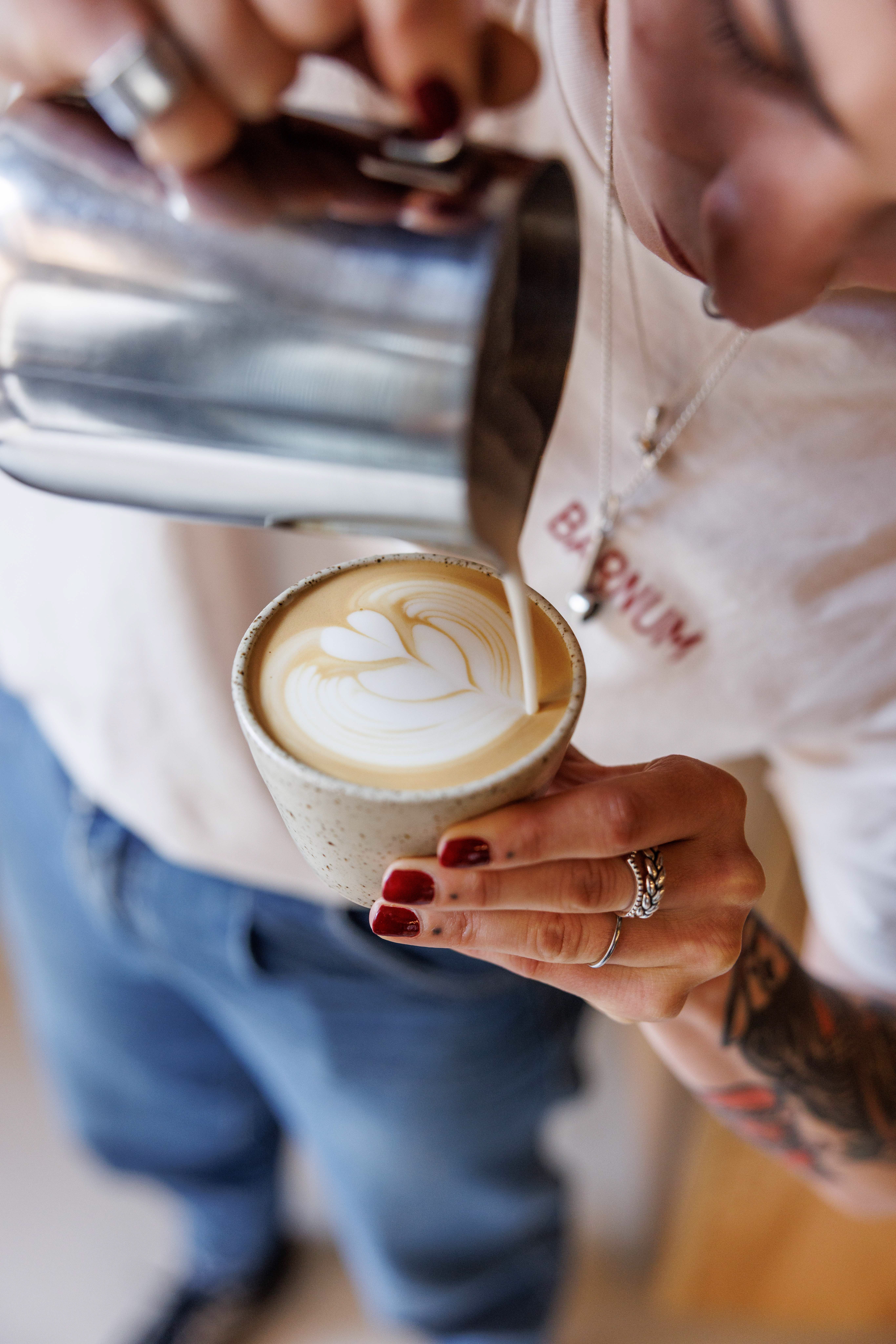 Barista pouring leaf latte art into a glass cup of coffee at Barnum, Rome, Italy