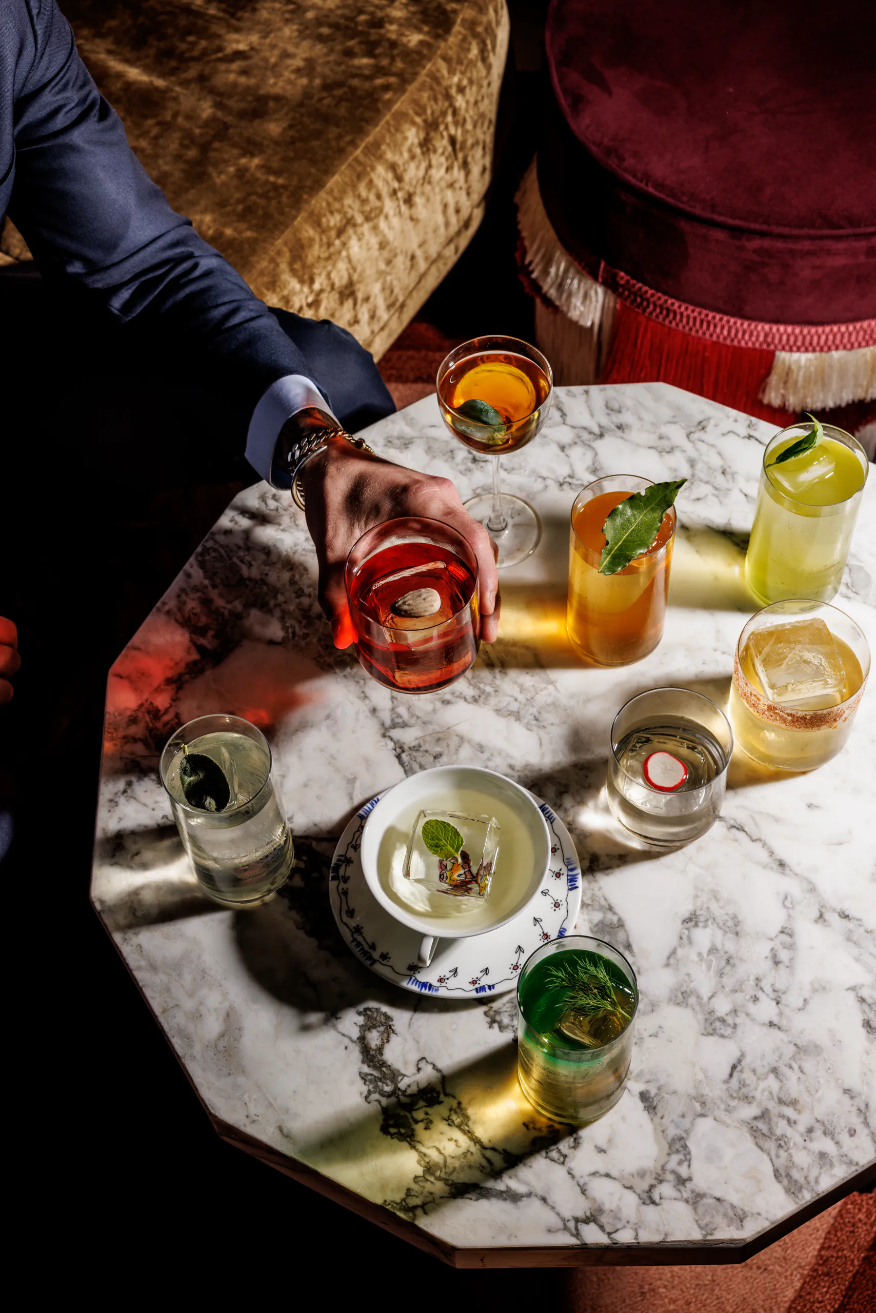 Marble table spread with several colourful cocktails and small dishes