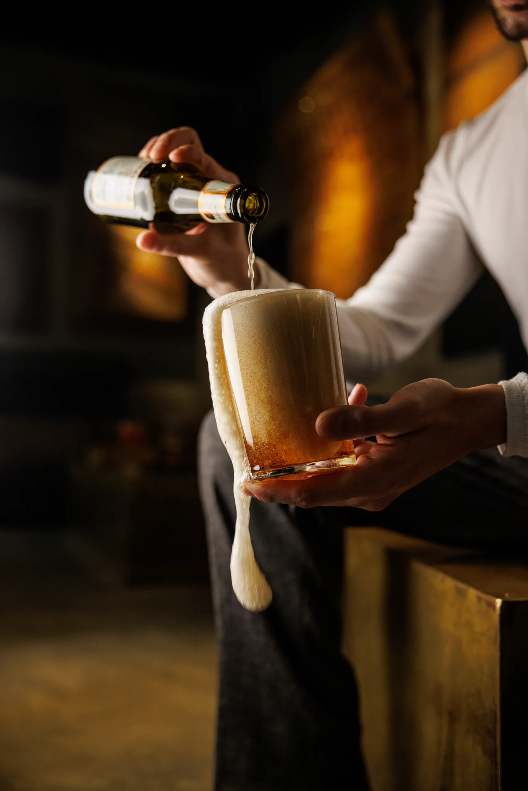 Bartender pouring a cocktail into a tall glass from a shaker in warm light — STRAF, Milan