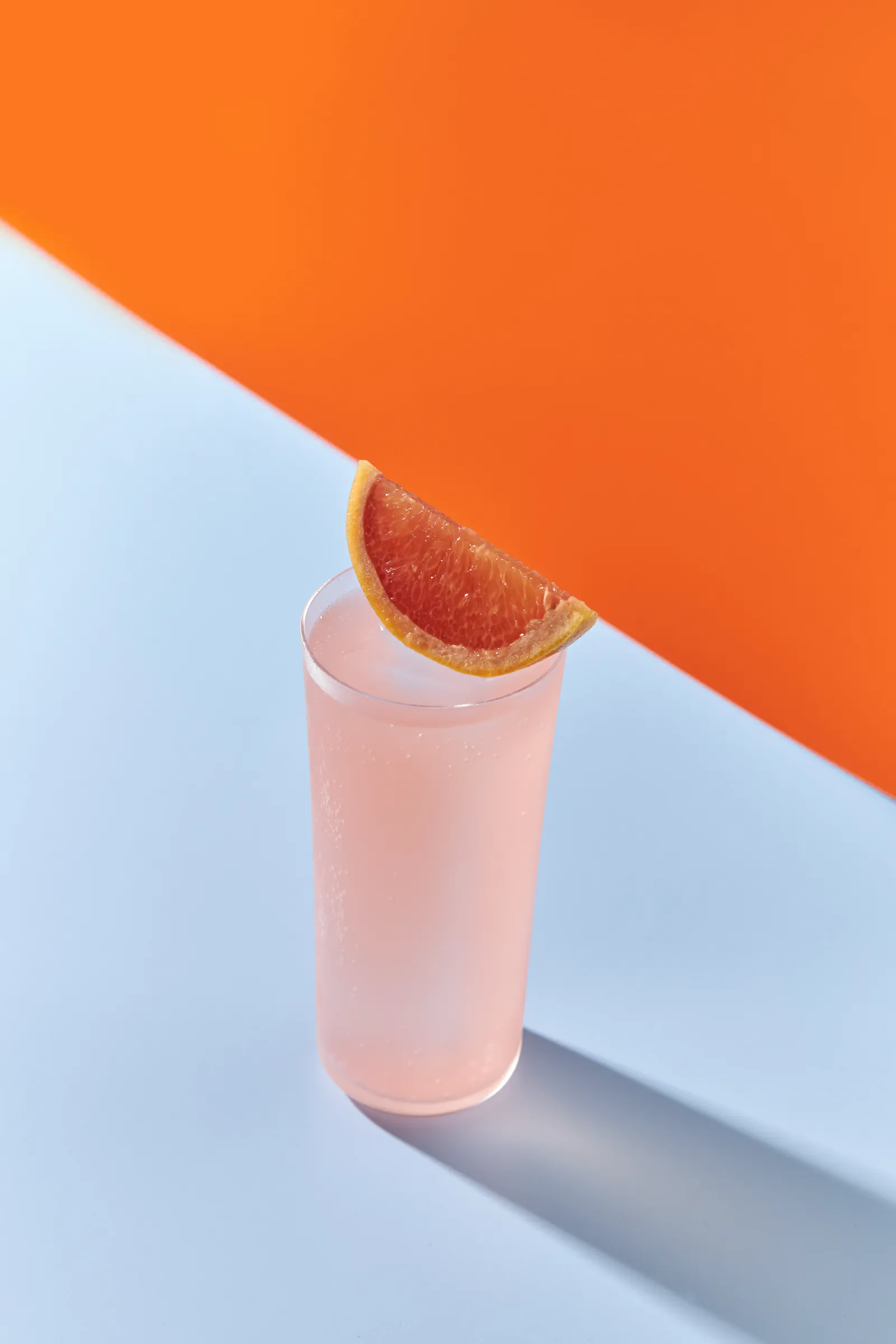 Pink grapefruit cocktail in a tall glass against a blue and orange background — Sabatini Gin, Milan
