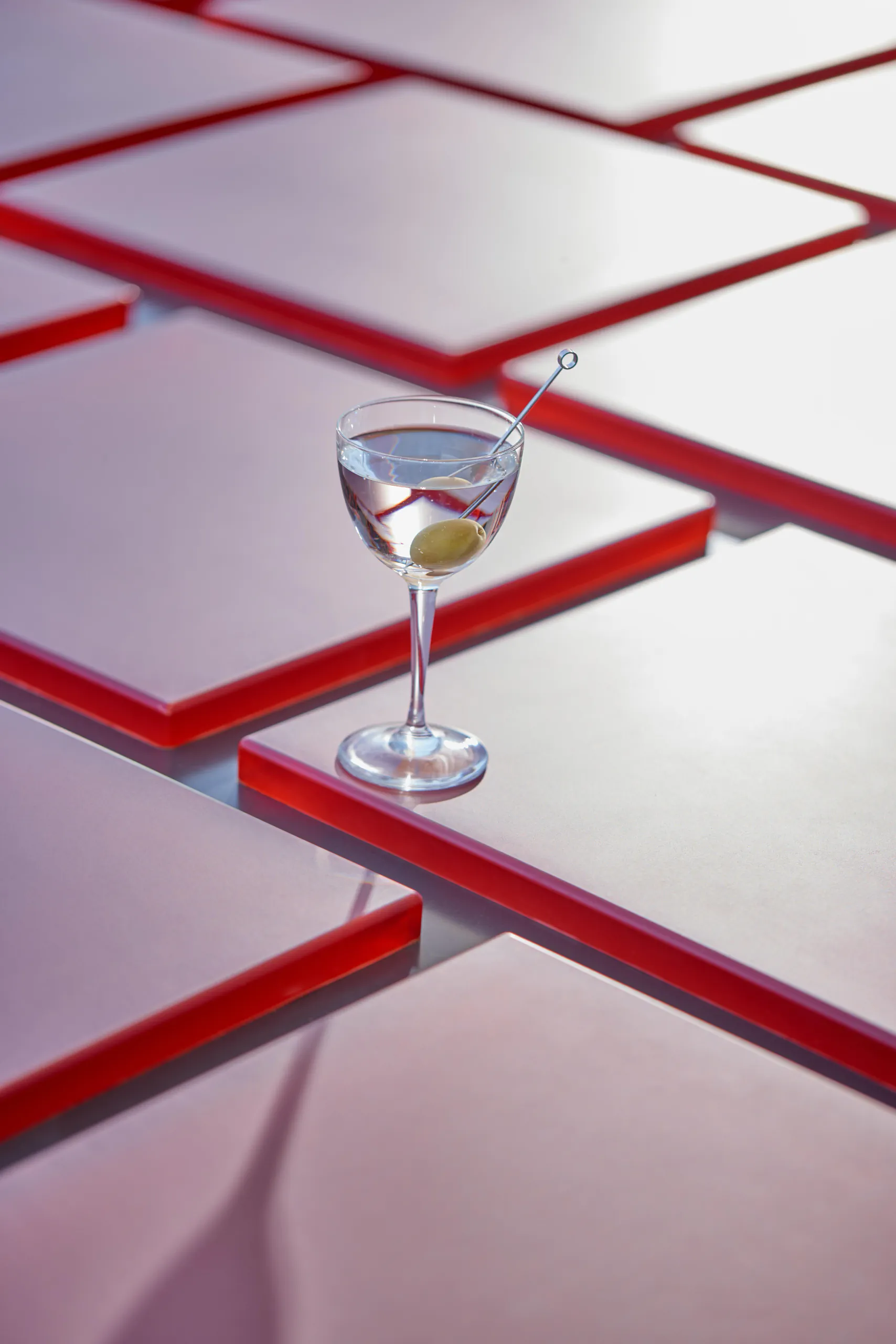 Martini with an olive on a red-edged glass shelf in a bright modern space — Torre, Fondazione Prada, Milan