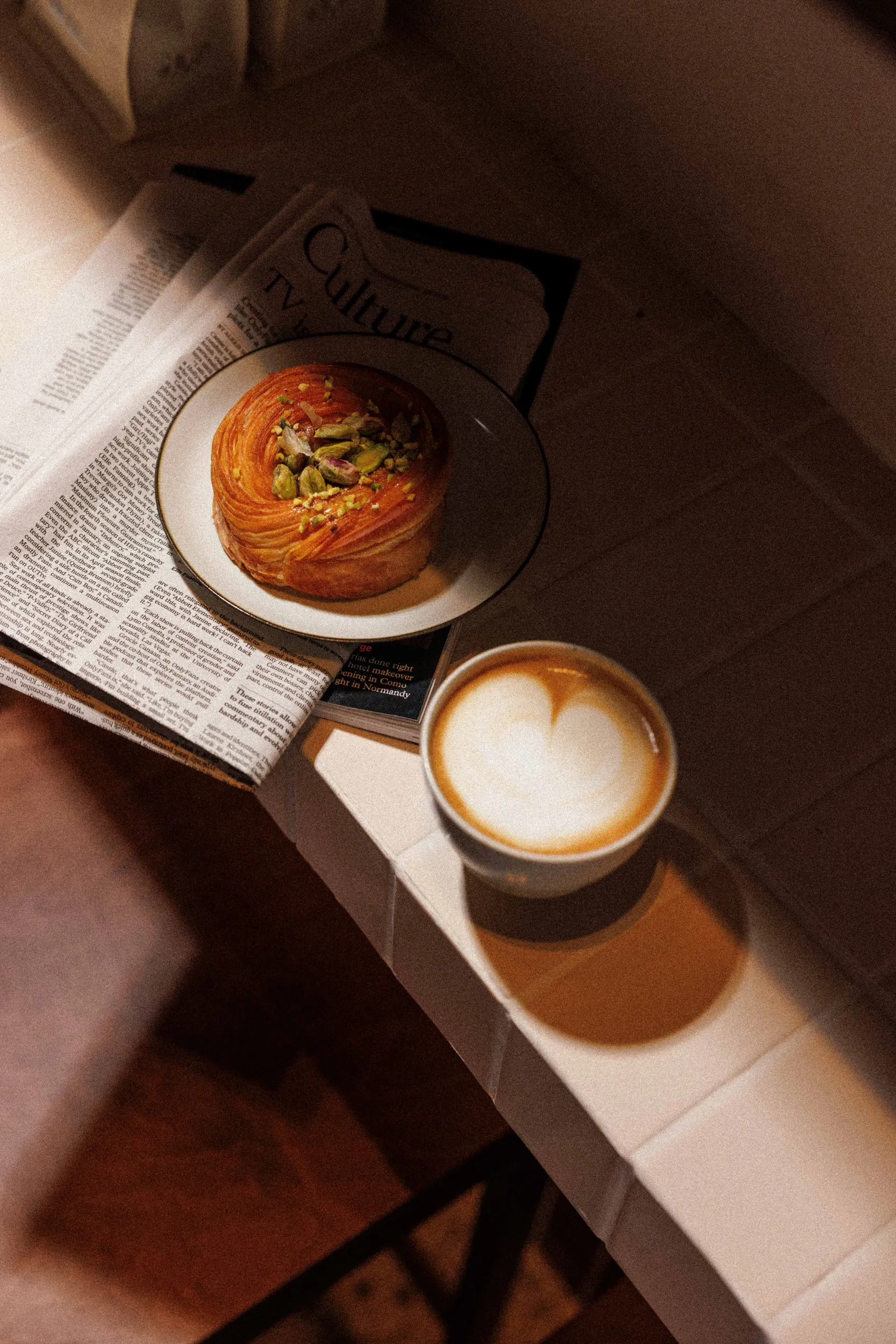 Cornetto pastry and cappuccino with latte art on a newspaper - cafe run by nuns, Rome, Italy