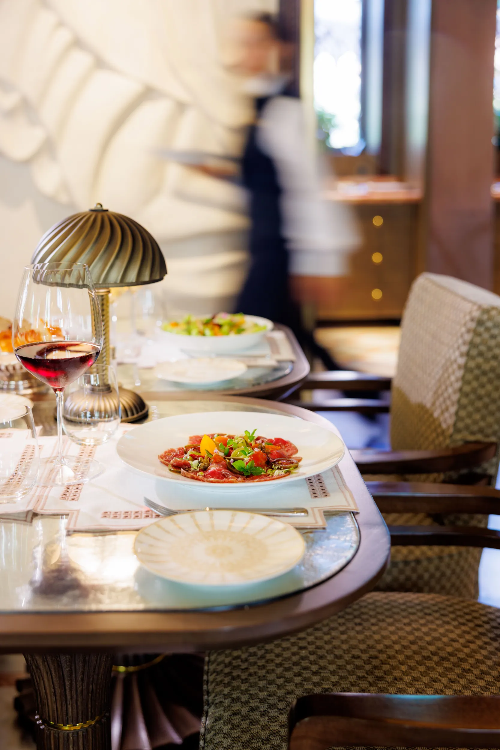 Elegant dining table with a plated dish and red wine - Orient Express Venezia, Venice, Italy