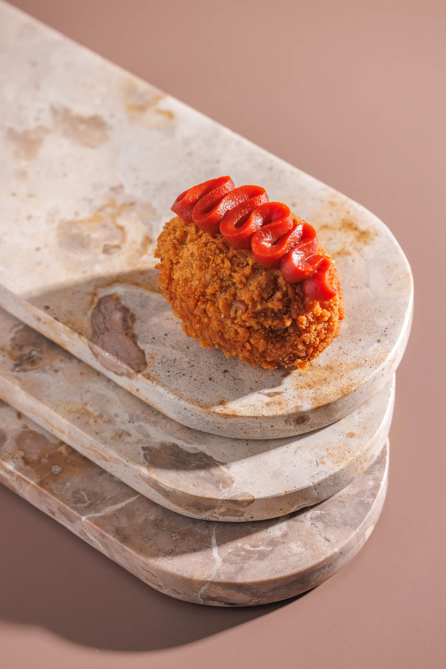 Fried croquette with a ketchup squiggle on stacked stone plates - Orma, Rome, Italy