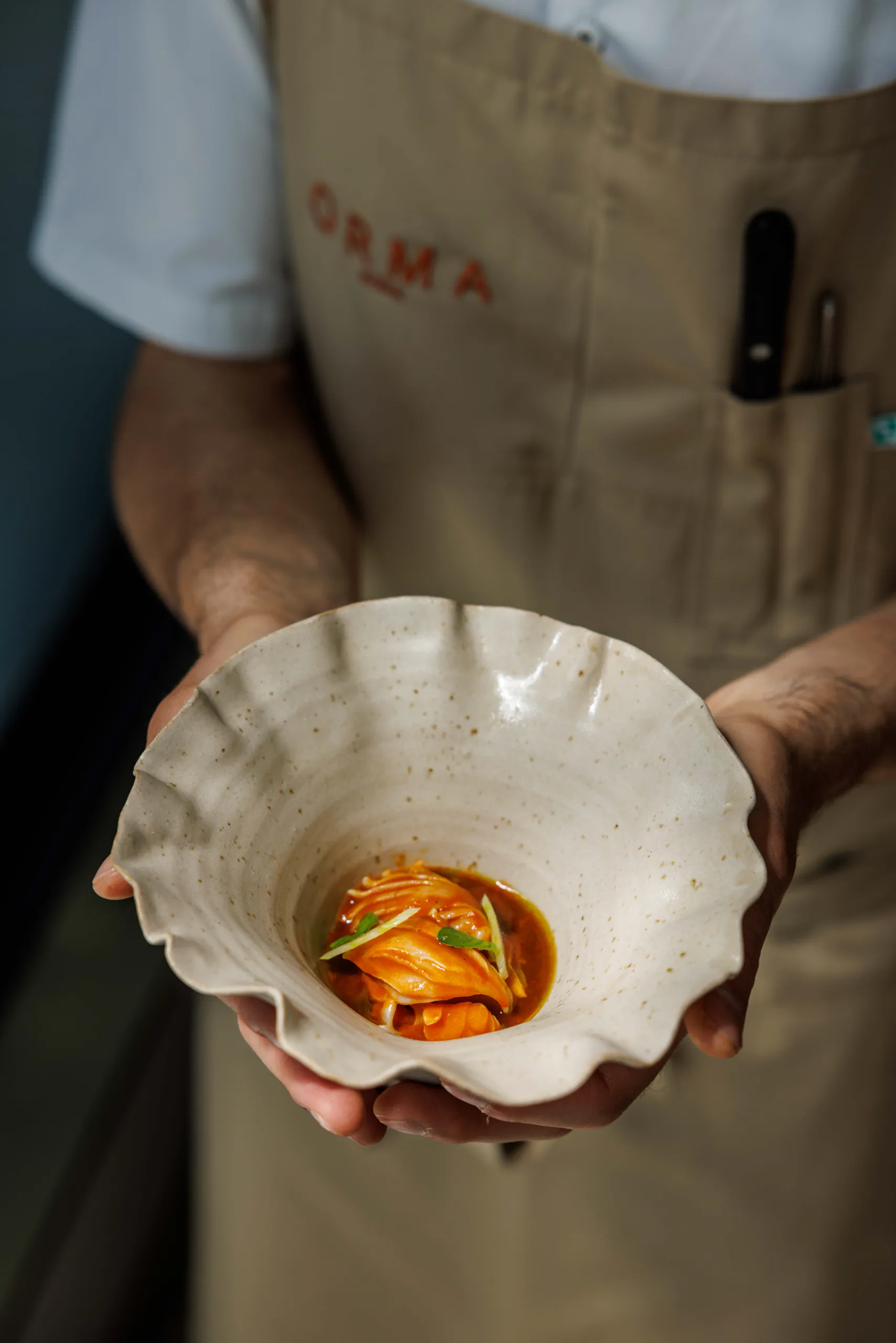 Chef holding a scallop-edged bowl with a plated dish - Orma, Rome, Italy