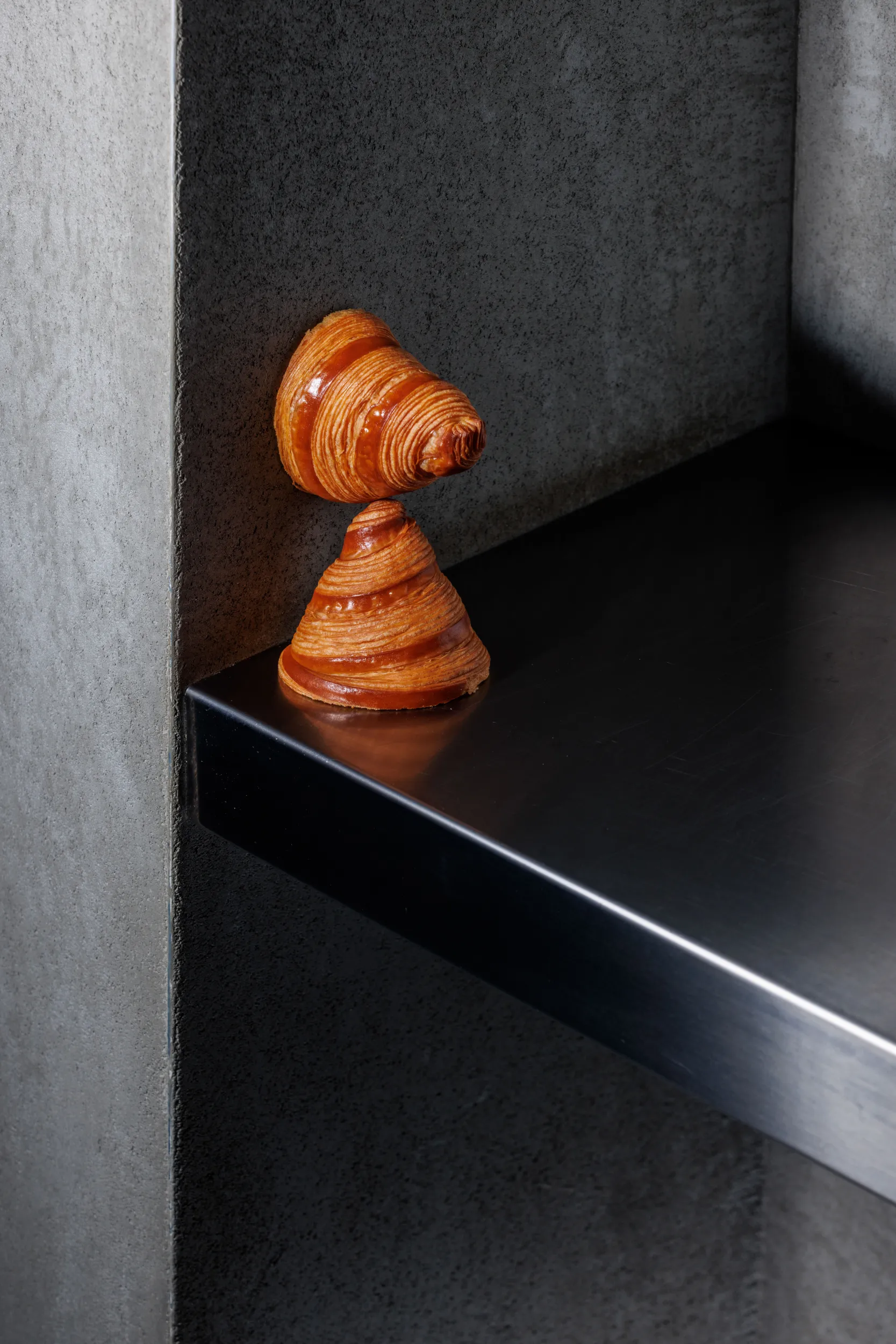 Golden cornetto pastry balanced on a stone ledge - Casa Manfredi, Rome, Italy