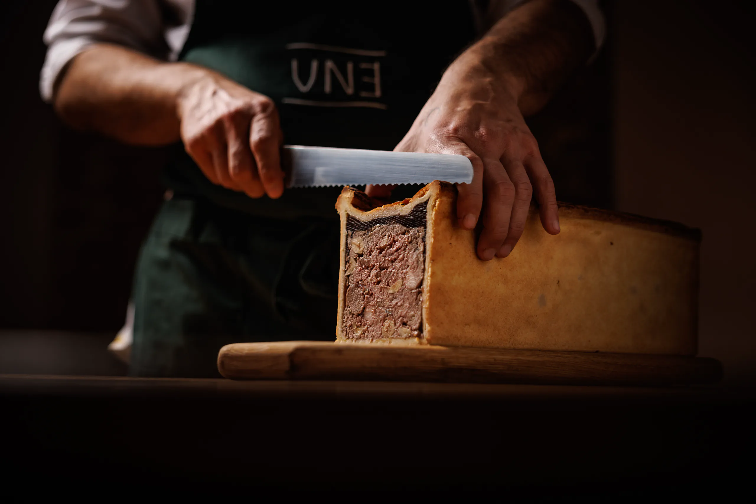 Chef slicing a raised meat pie (pate en croute) - UNE, Capodacqua, Italy