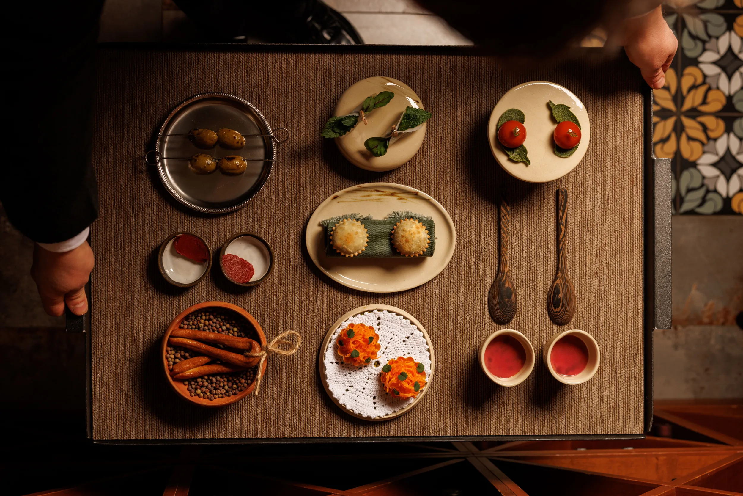 Array of appetizer bites and condiments on a wooden tray, seen from above - Bistrot64, Rome, Italy