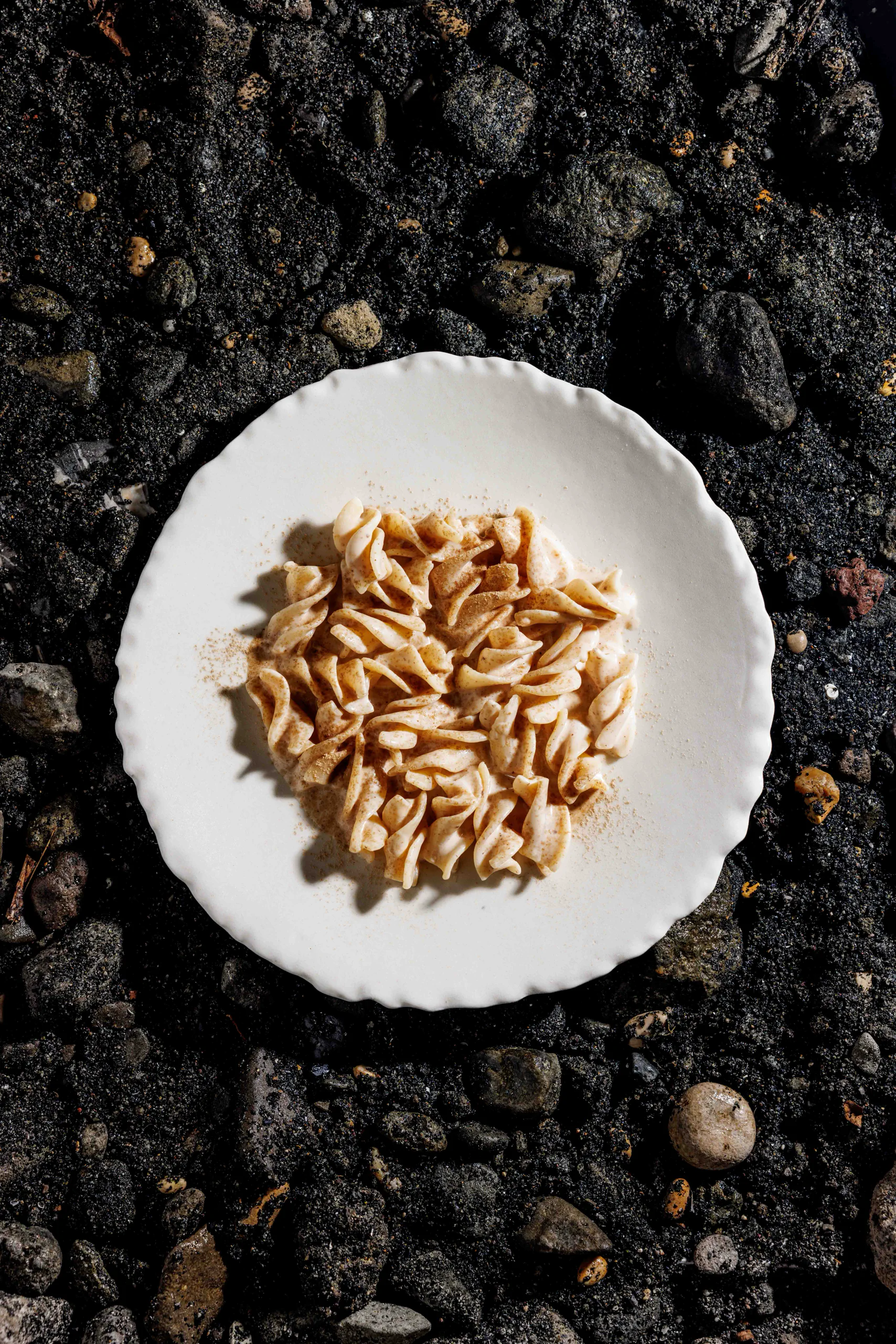Plate of pasta on black volcanic gravel - Sintesi, Rome, Italy