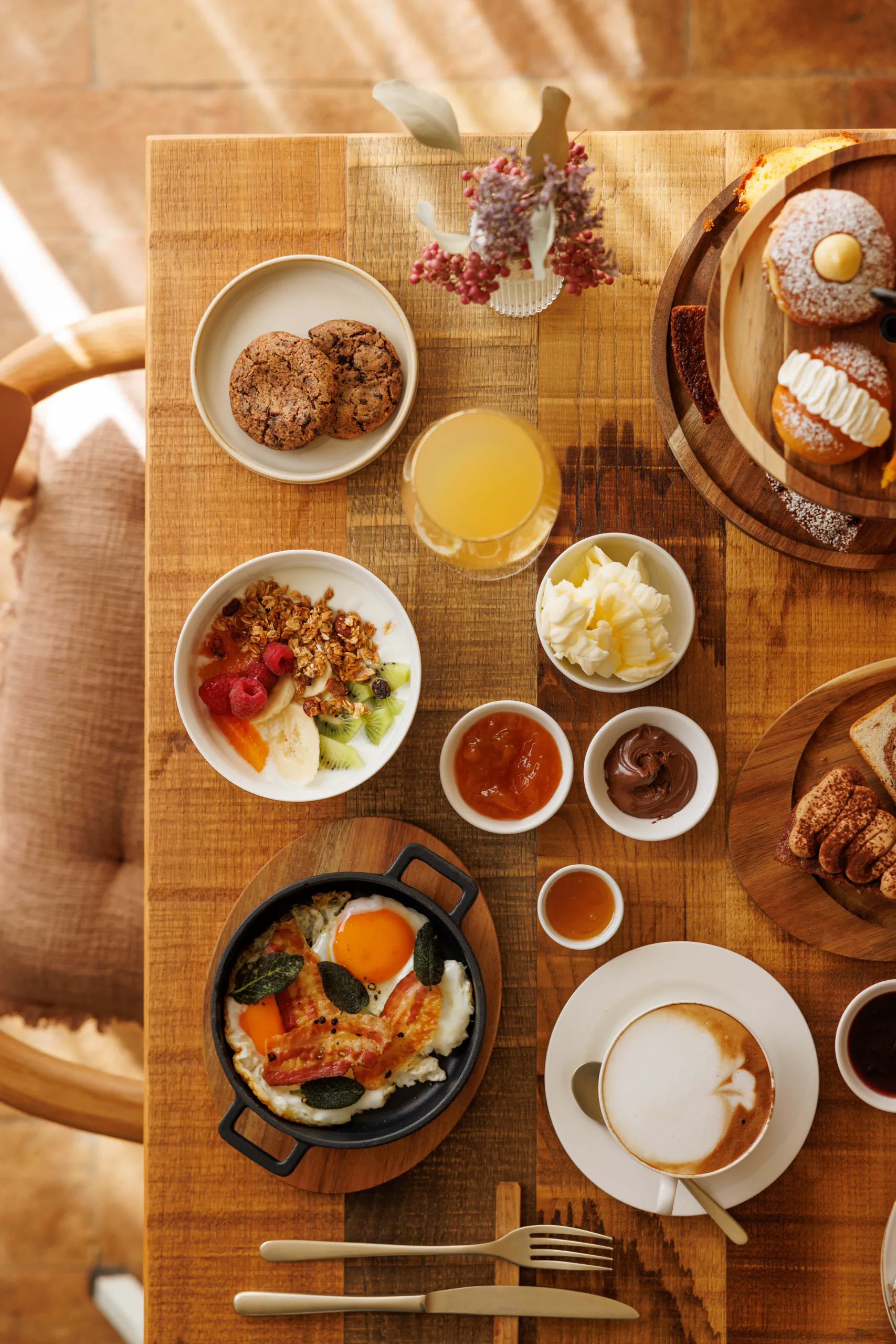 Rustic breakfast spread with pastries, eggs and cappuccino, seen from above
