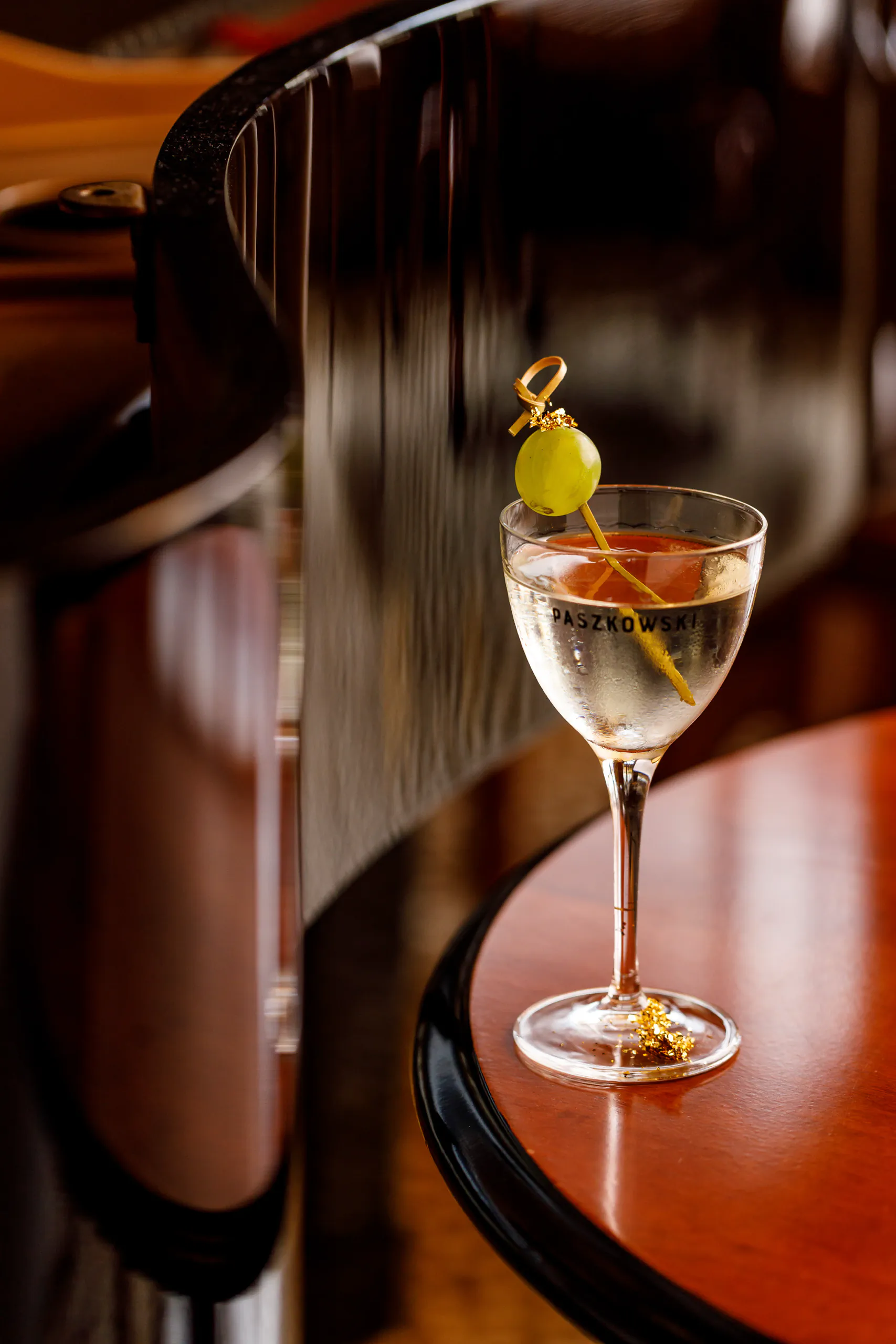 Gibson cocktail with a skewered onion garnish on a round wooden bar table
