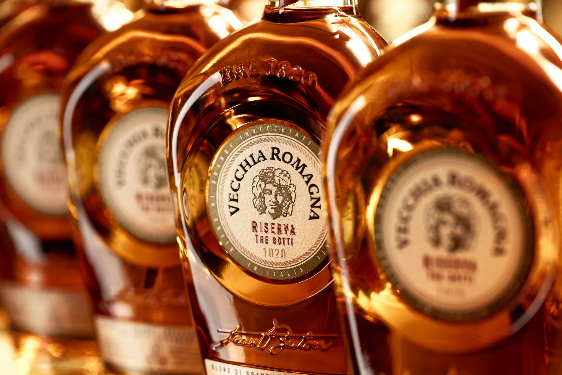 Row of Vecchia Romagna brandy bottles in warm amber light