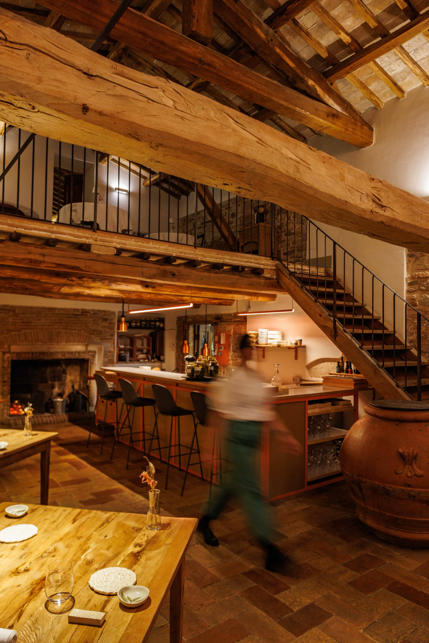Rustic wood-beamed interior with a staircase and warm lighting
