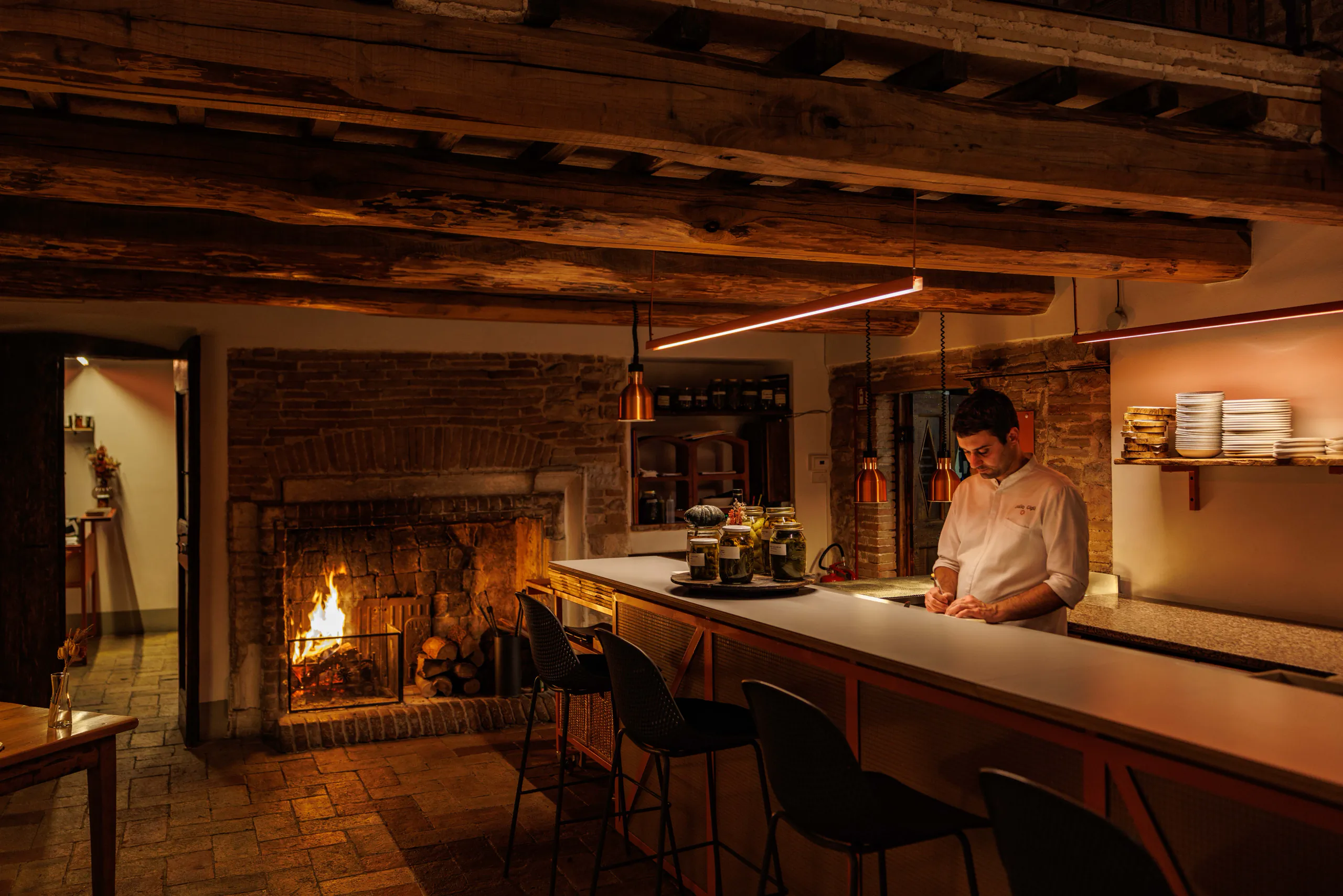 Rustic bar with a lit fireplace and a bartender behind a wooden counter