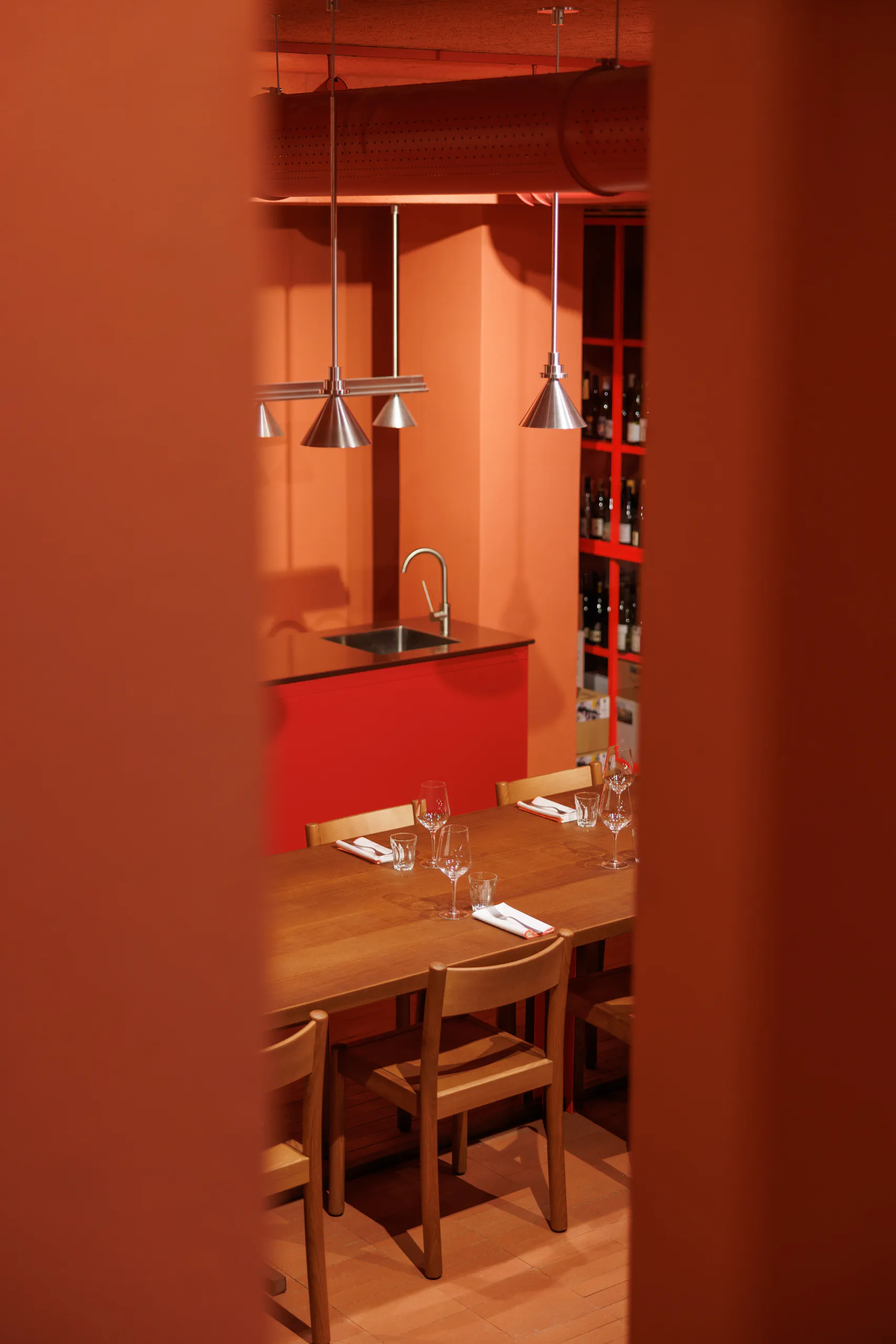Warm terracotta private dining room with a set wooden table and wine bottles