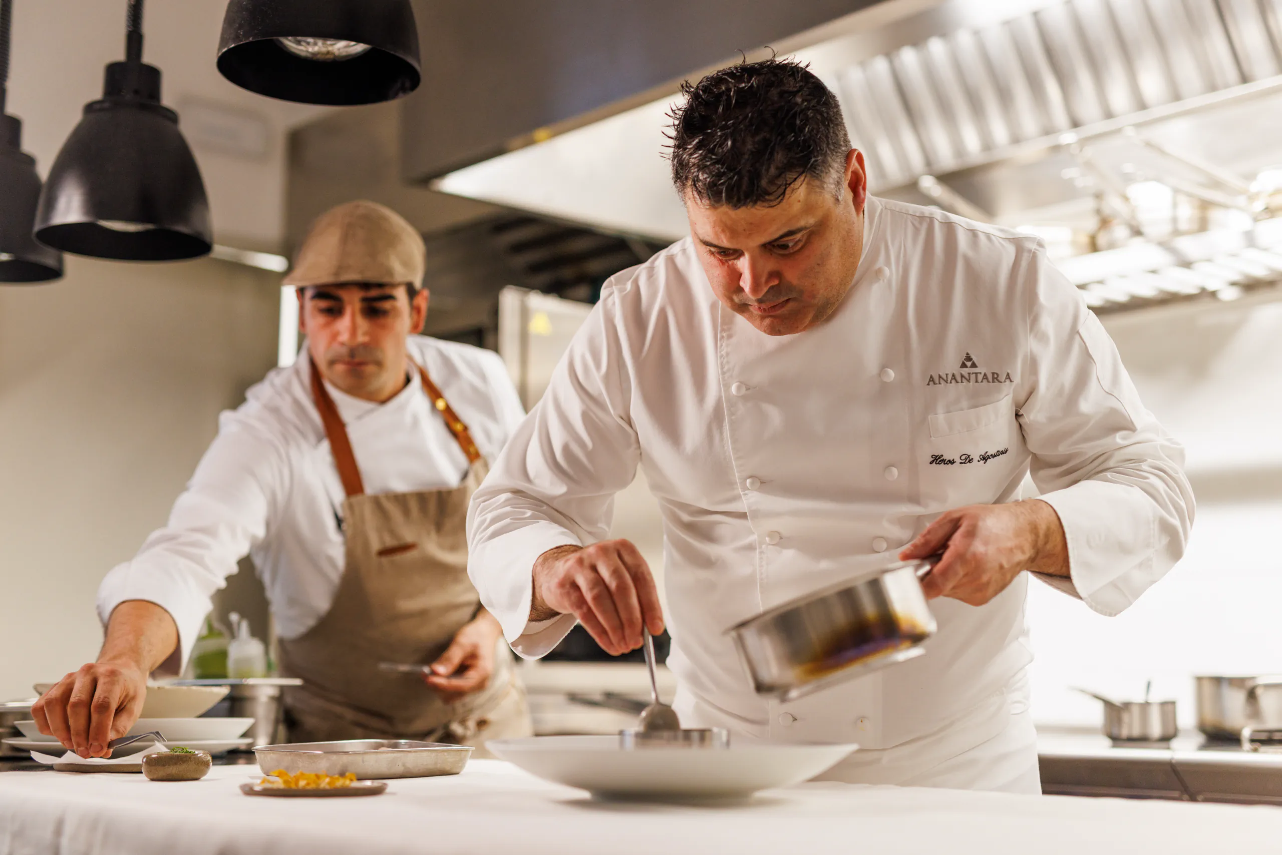 Two chefs in whites plating dishes in a professional kitchen