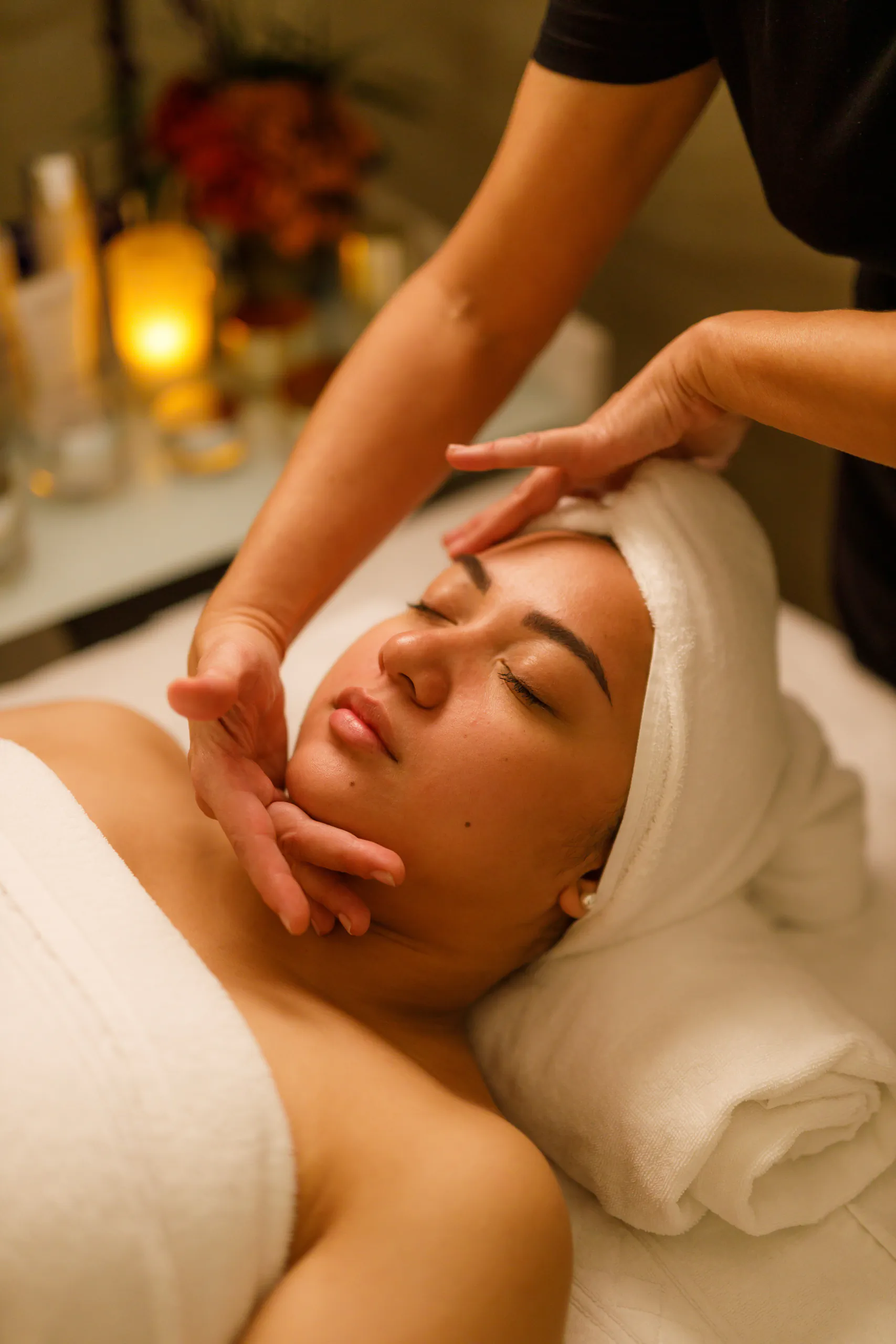 Person receiving a facial treatment at a spa, wrapped in towels