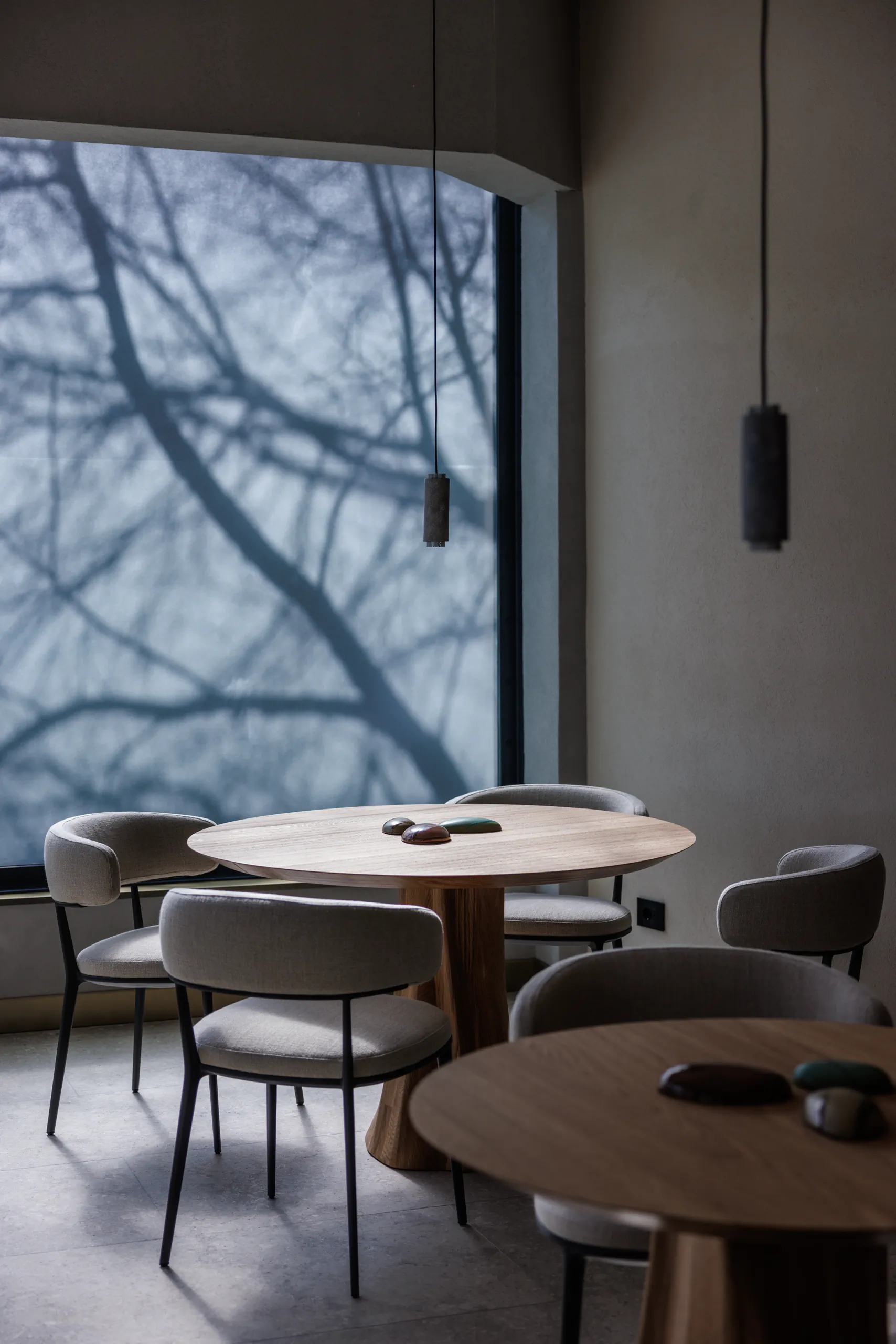 Bright dining room with round tables by a large window overlooking bare trees