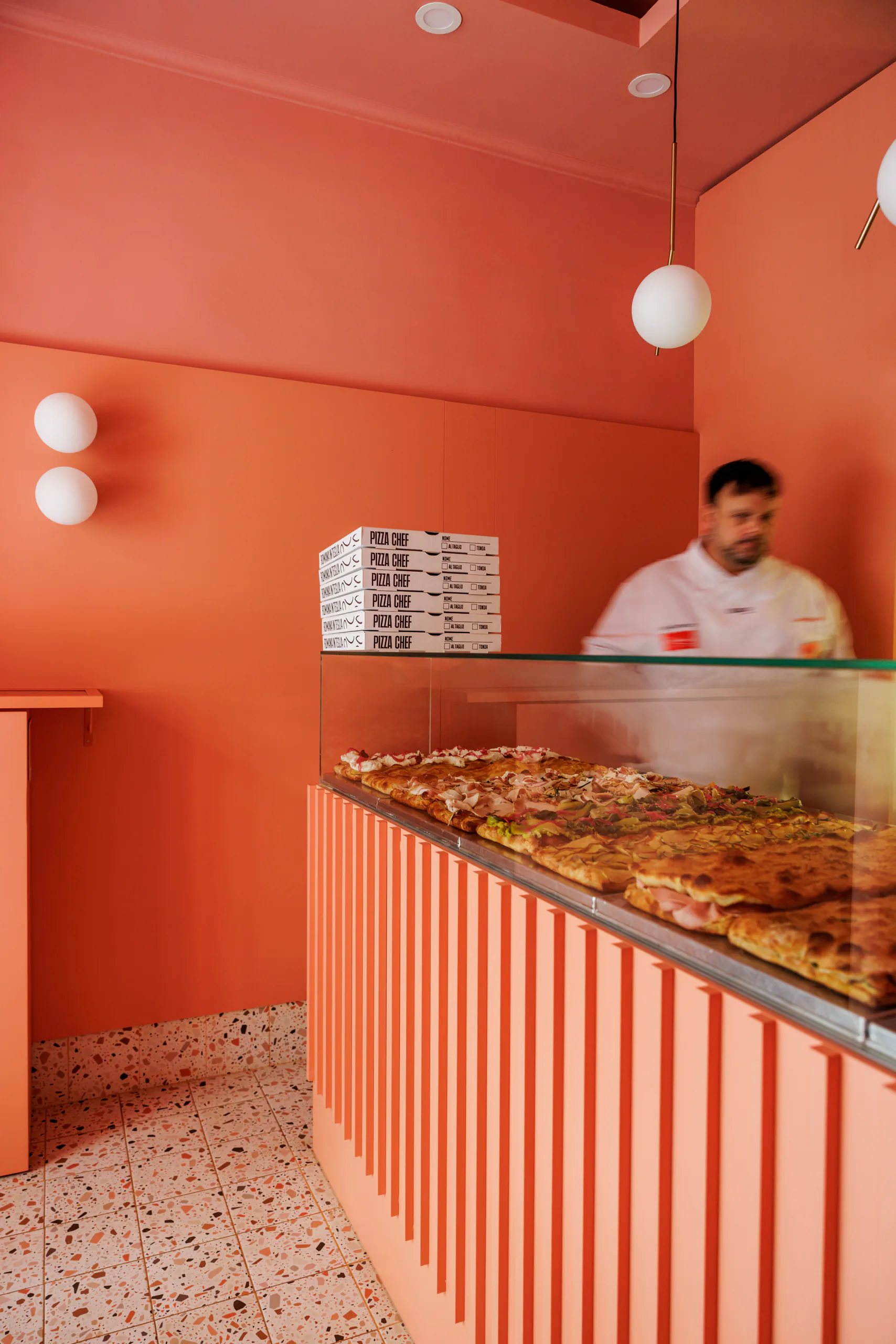 Orange-toned bakery counter with pastries on display and staff behind it
