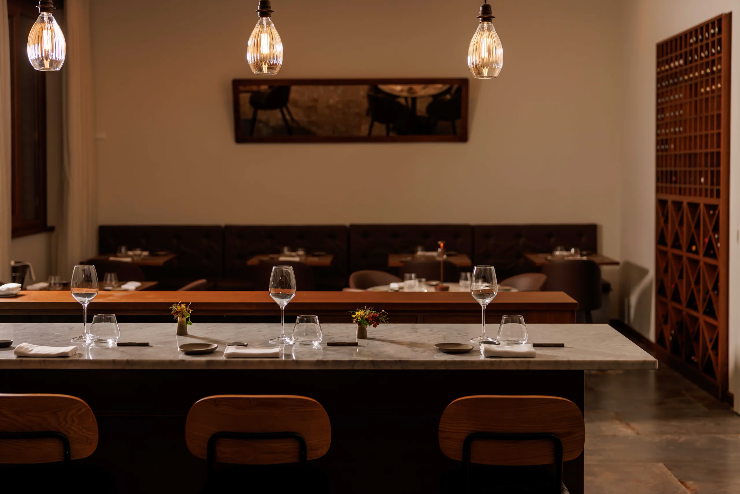 Elegant restaurant with a long stone table, leather chairs and banquette seating