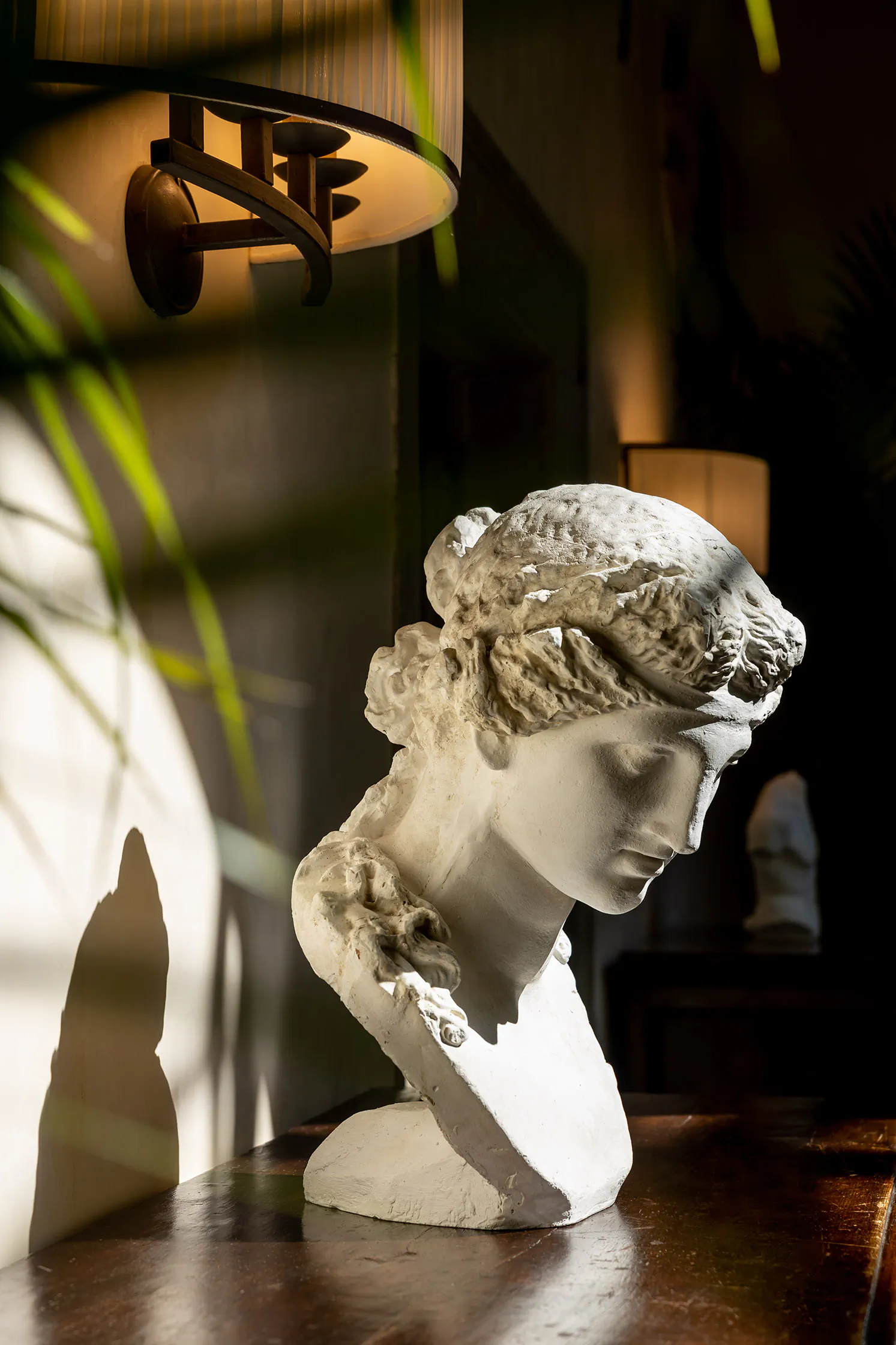 Classical marble bust on a stand in a warmly lit room