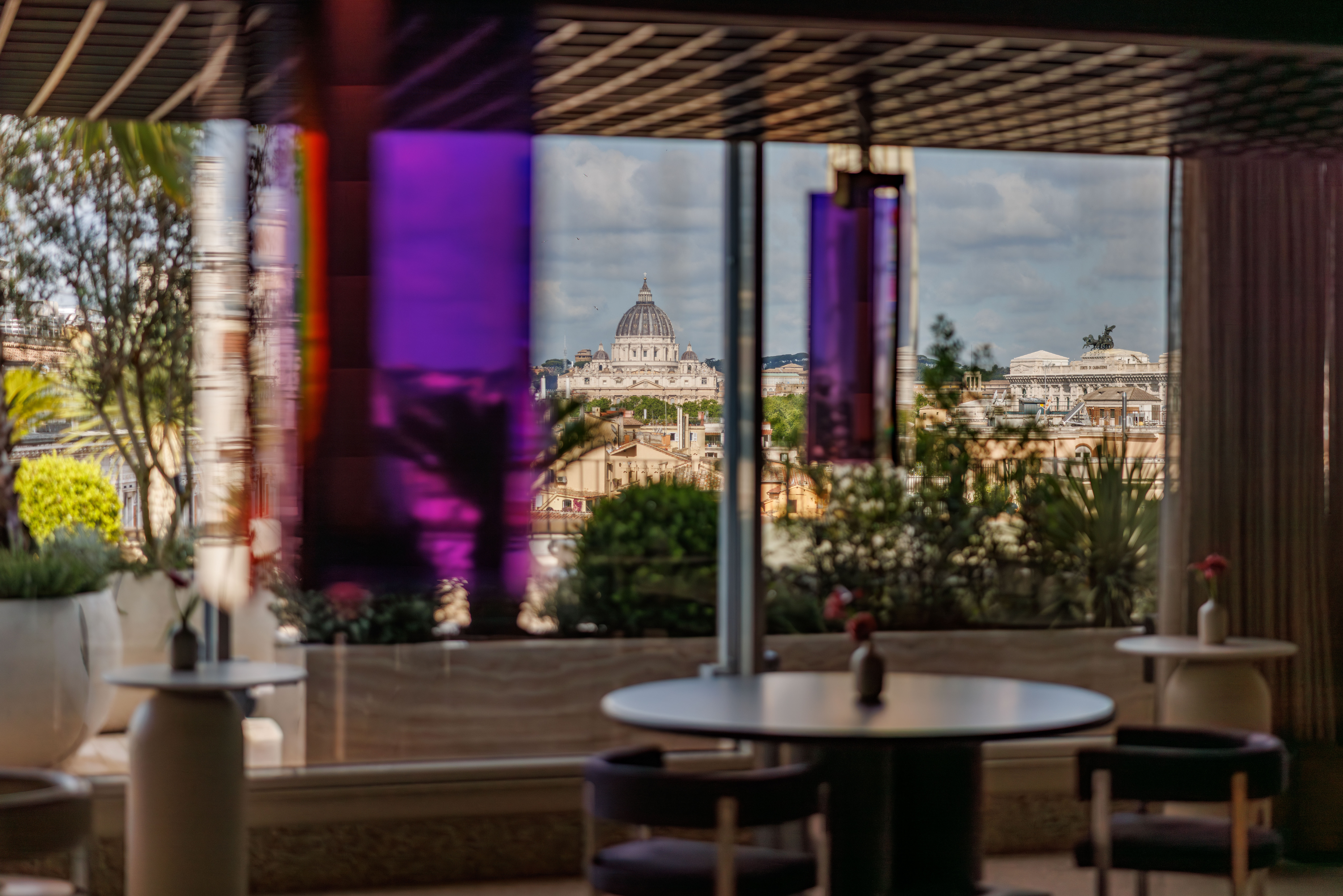 Rooftop terrace bar at dusk with purple lighting overlooking Rome