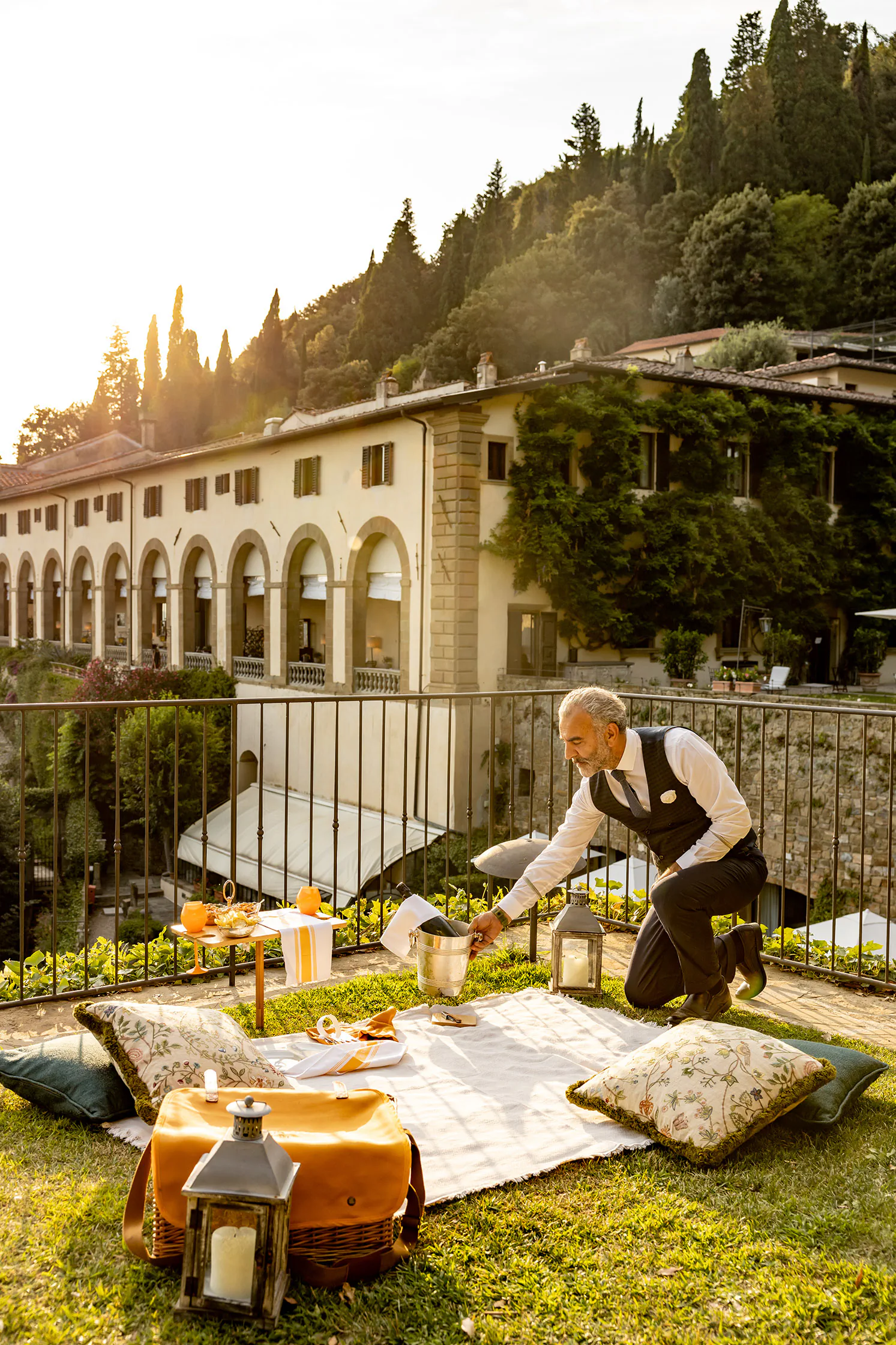 Garden terrace on a hillside with lounge cushions and a historic building behind