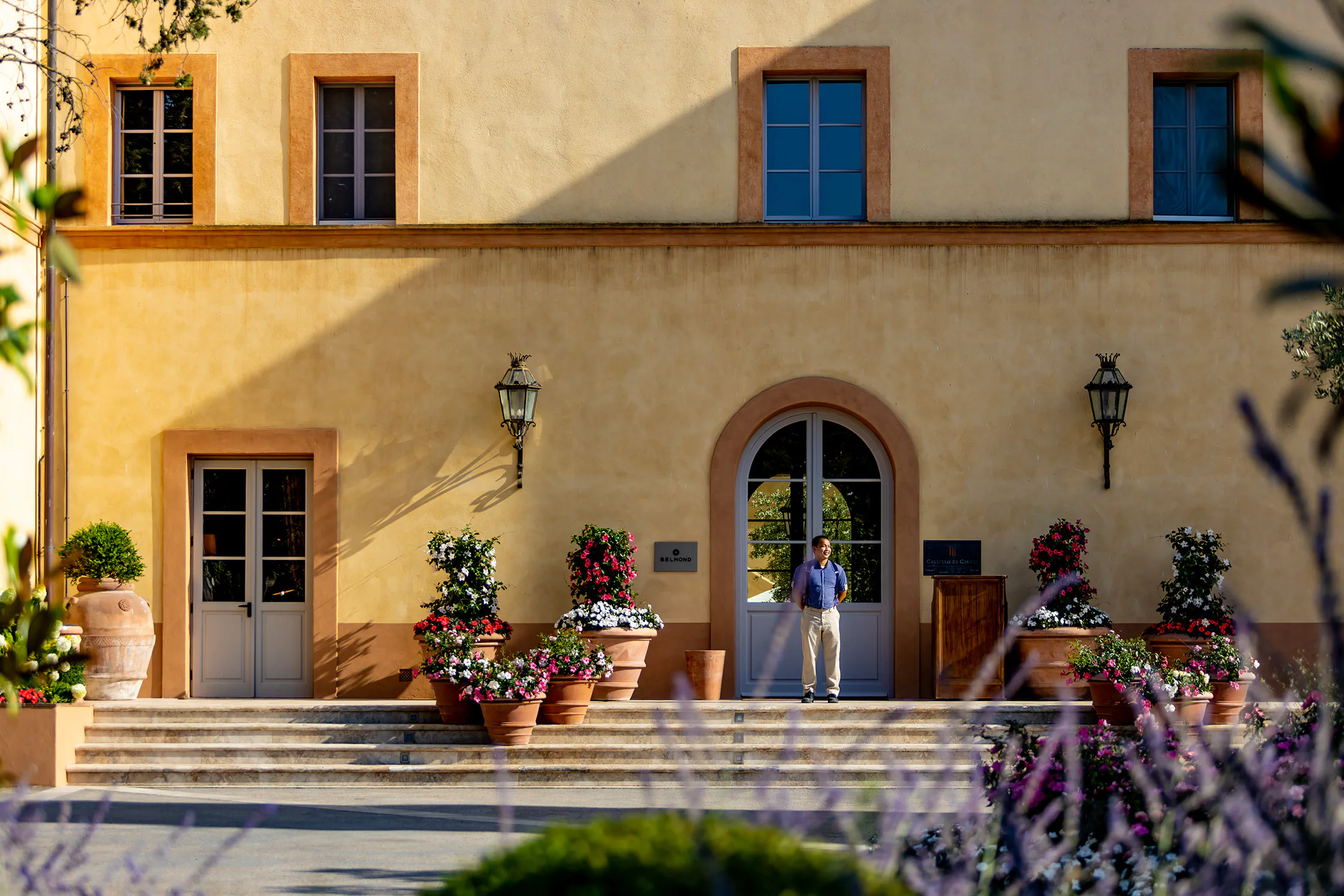 Mediterranean villa exterior with arched doorways, potted plants and wisteria