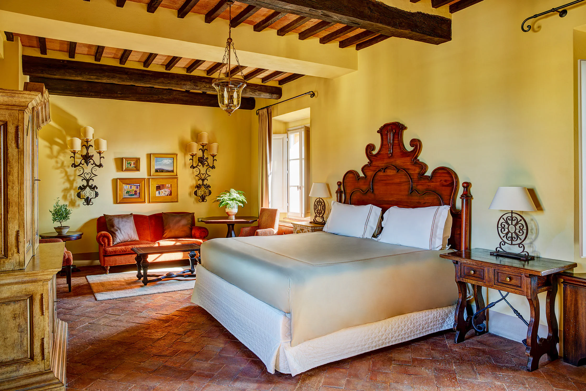 Rustic Tuscan bedroom with a carved wooden headboard and beamed ceiling