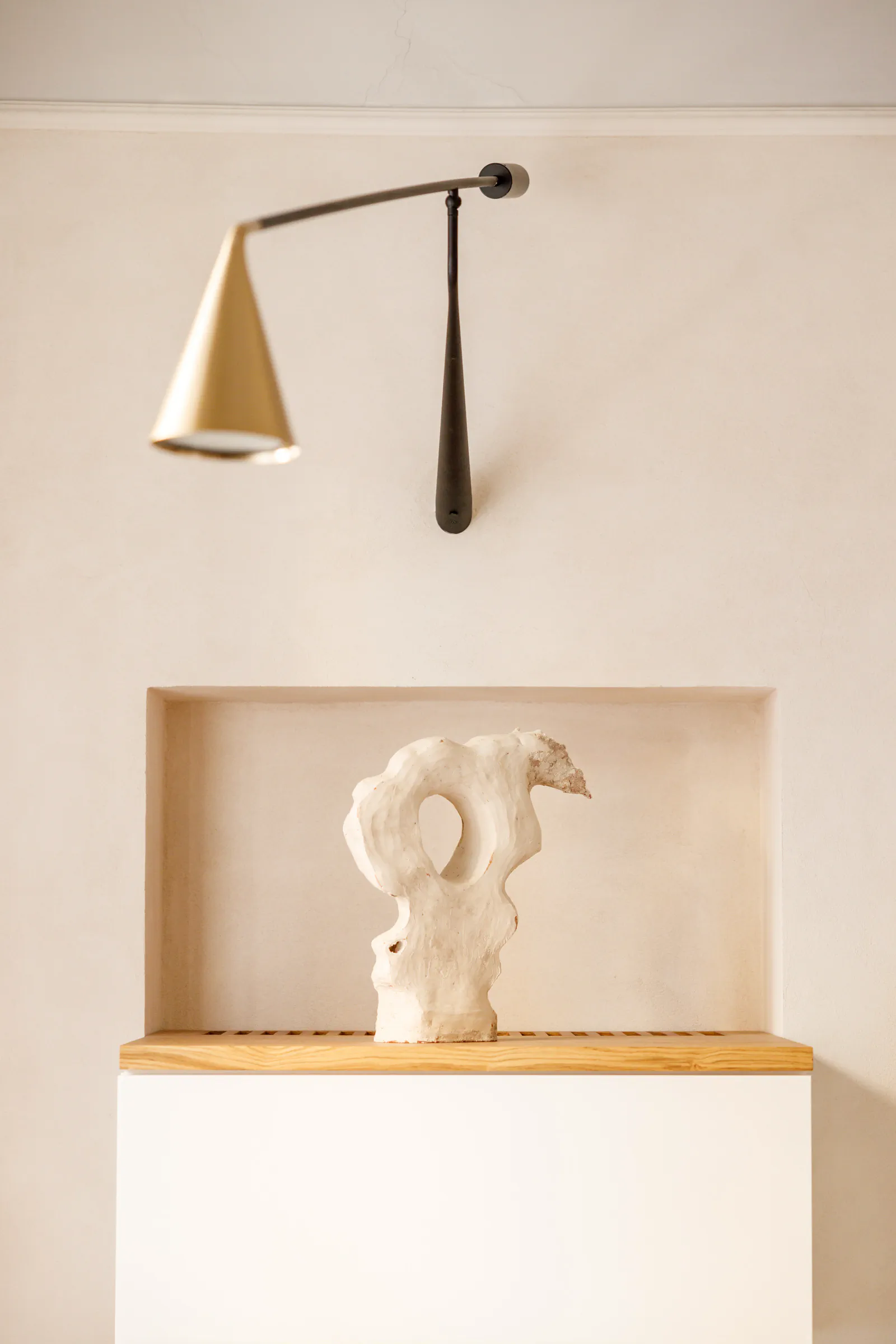 Minimalist wall with a sconce lamp and a small sculpture on a ledge
