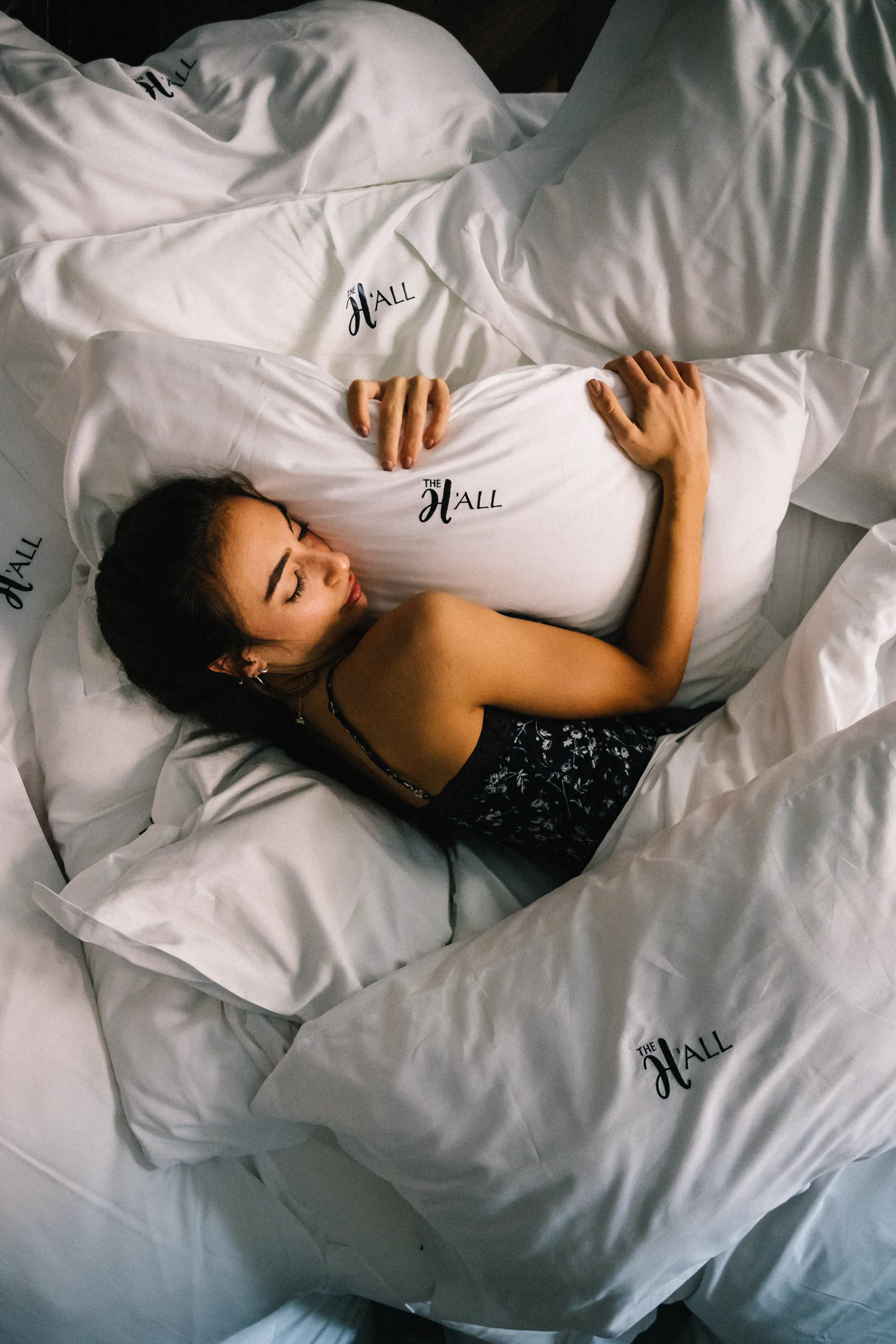 Person relaxing in white bed linens seen from above