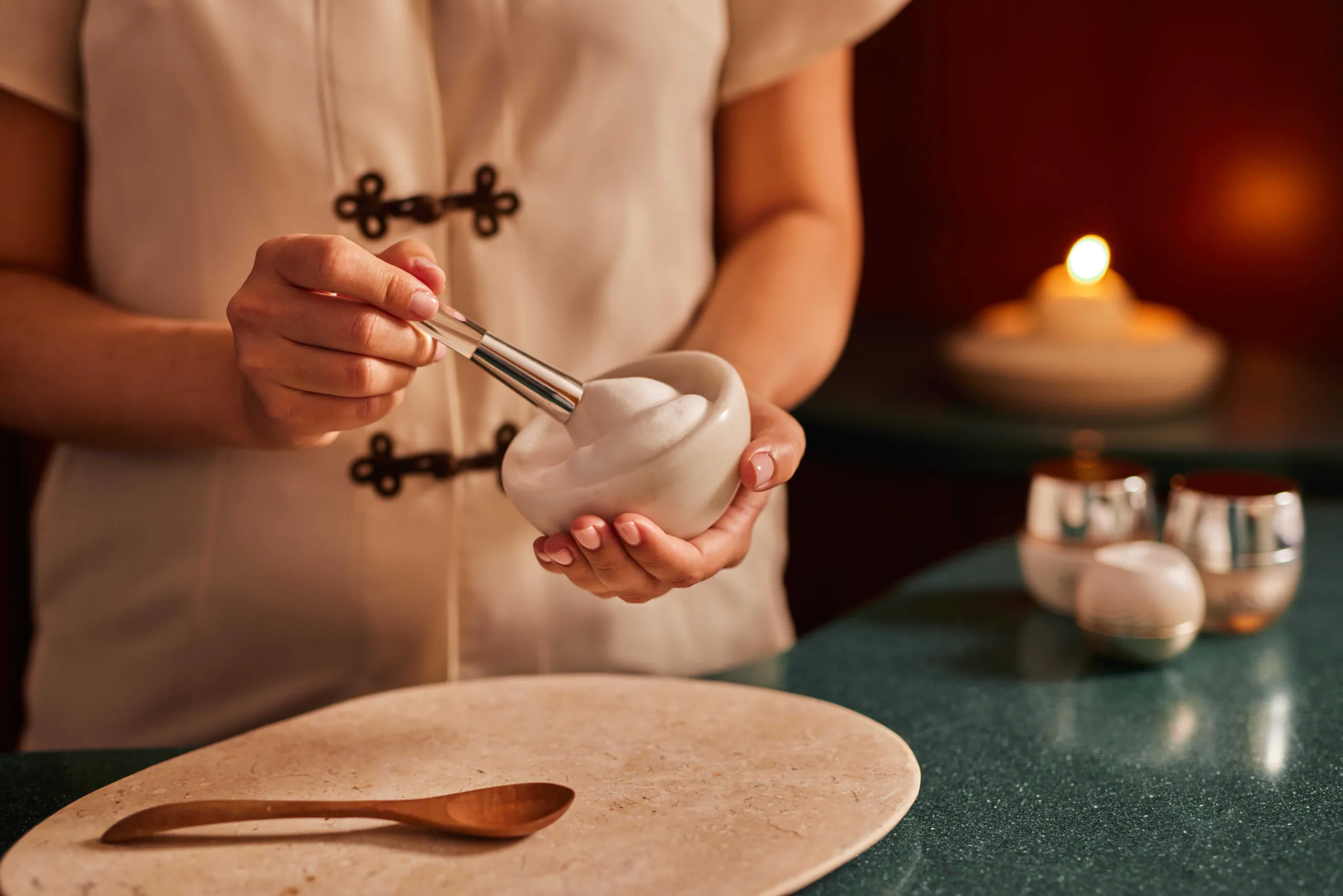 Hands holding a bowl during a candlelit spa ritual — Hotel Principe di Savoia, Milan