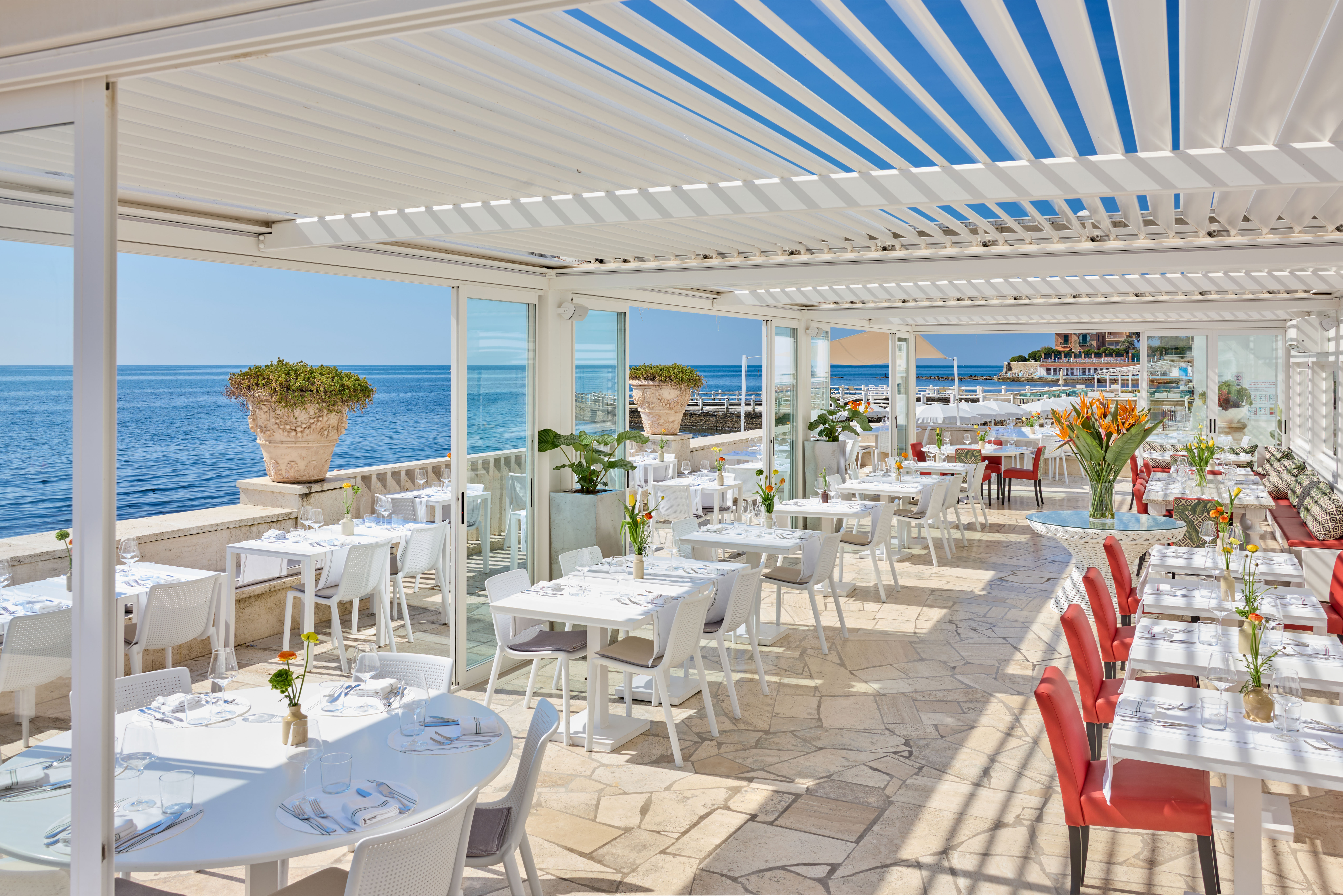 Seaside terrace restaurant with white-set tables overlooking the sea — Bianca