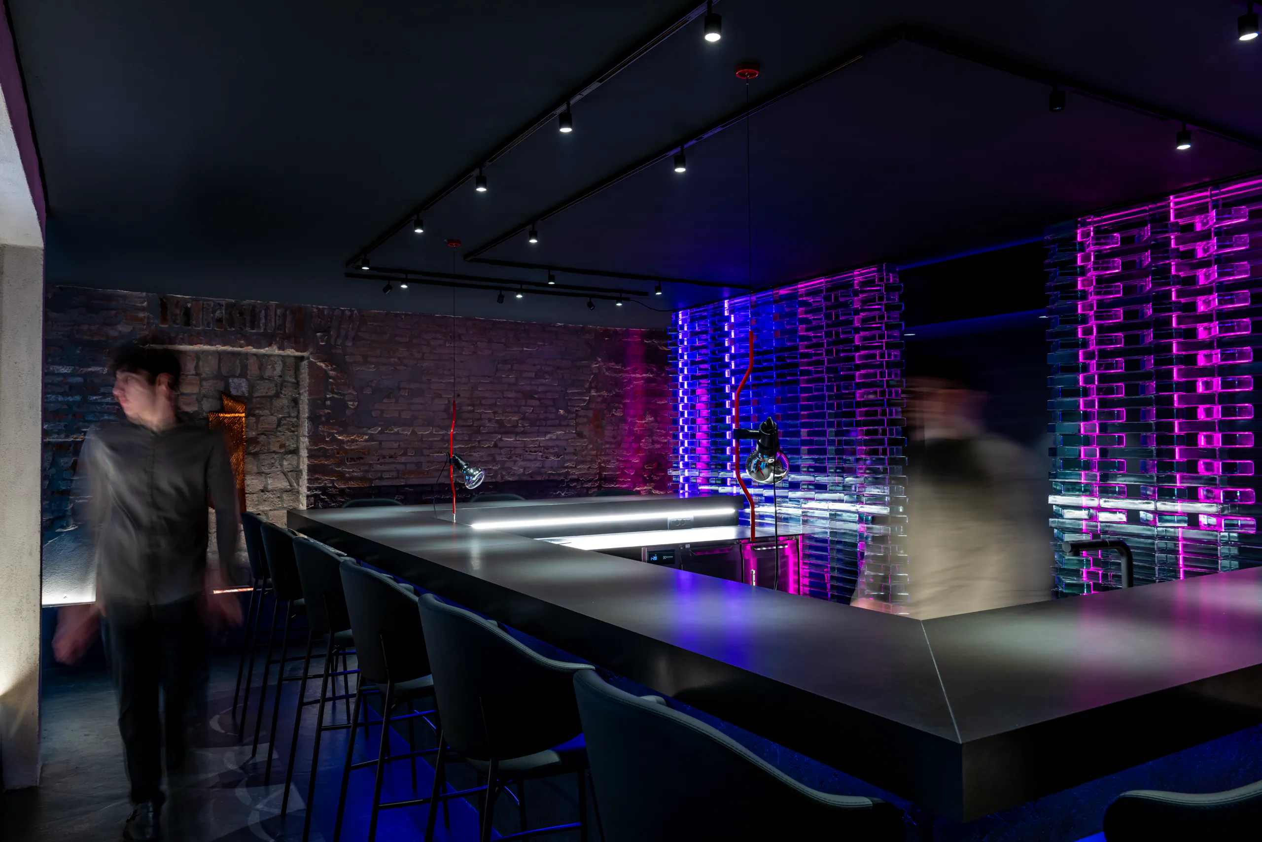 Dark lounge bar with purple and blue backlit wine racks