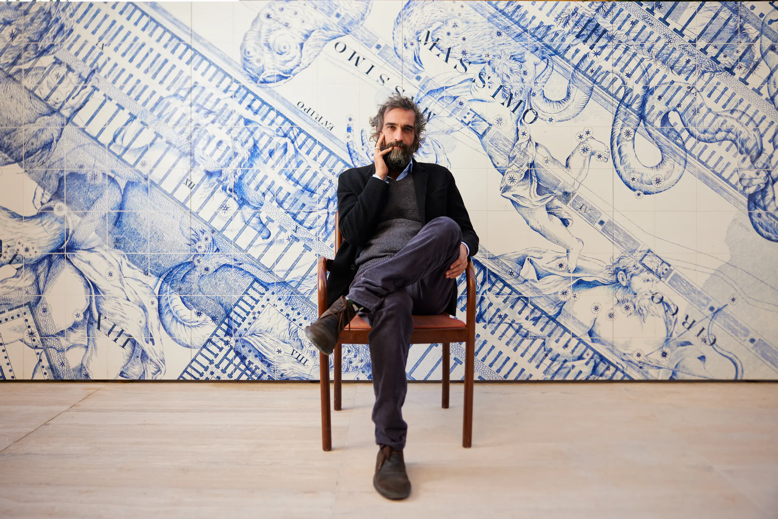Man seated in front of a large blue architectural-drawing mural — art'otel, Rome