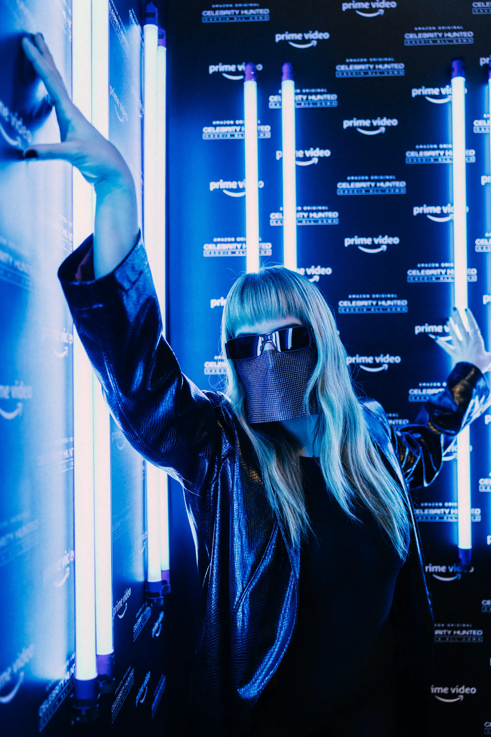 Woman raising her arm against a blue-lit press backdrop