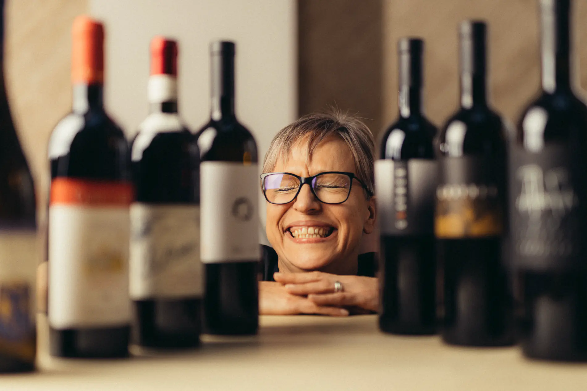 Smiling woman with glasses among rows of wine bottles