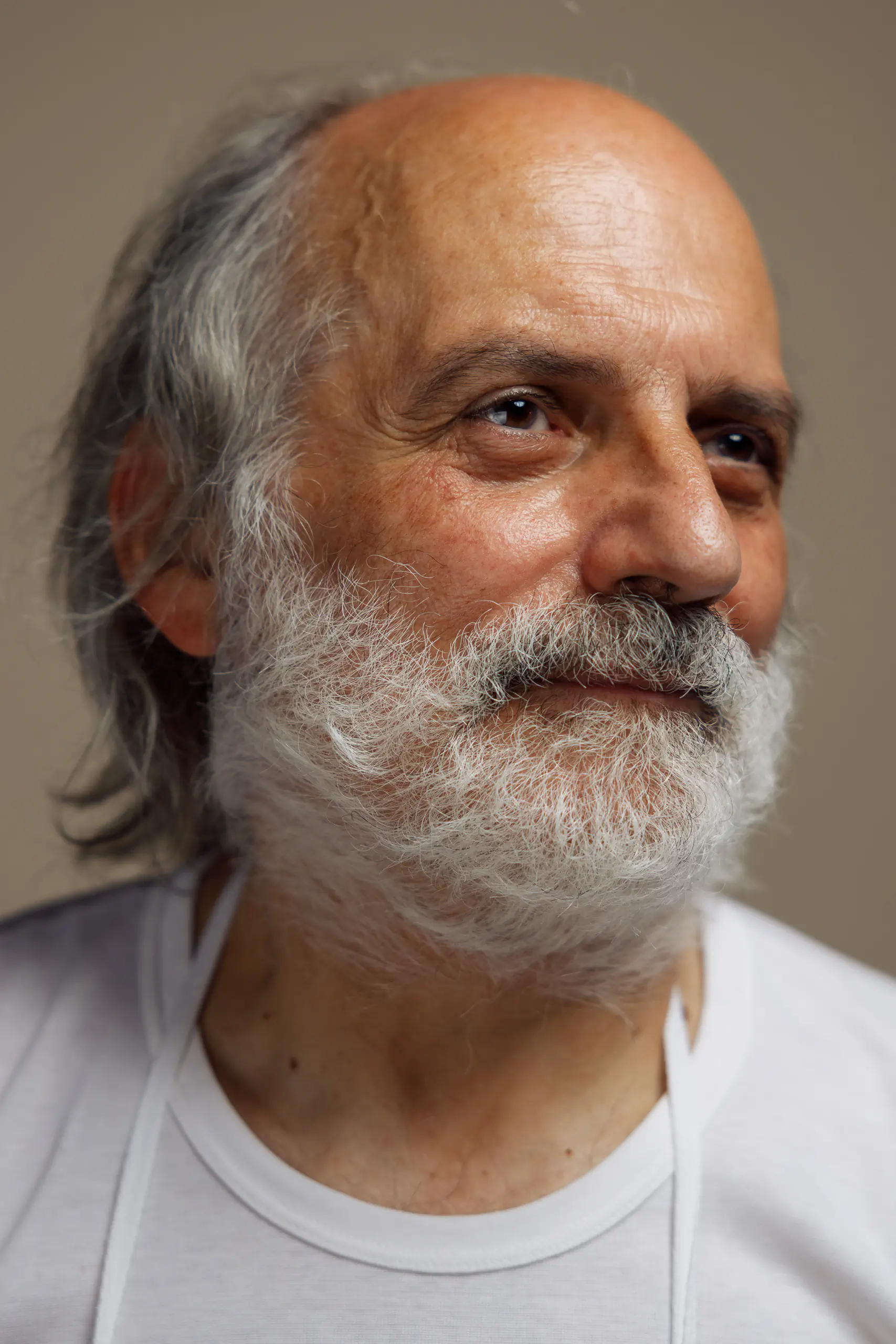 Portrait of an older man with a grey beard in a white t-shirt