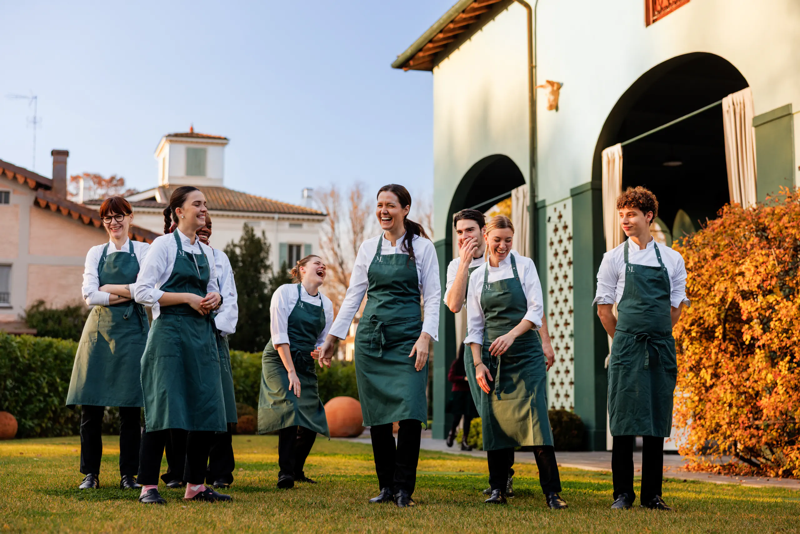 Group of staff in aprons on a lawn in front of a villa