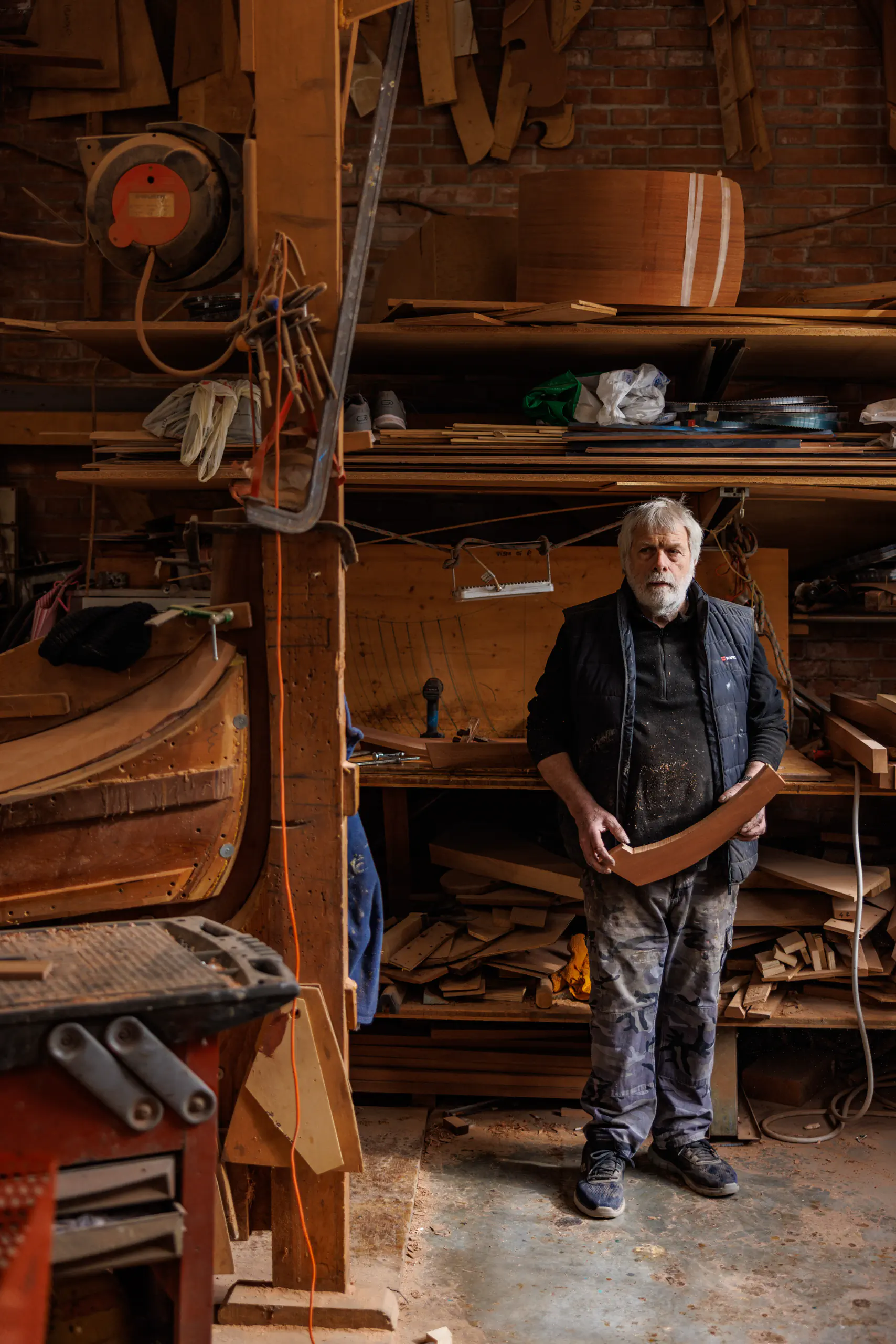 Older man standing in a workshop surrounded by tools