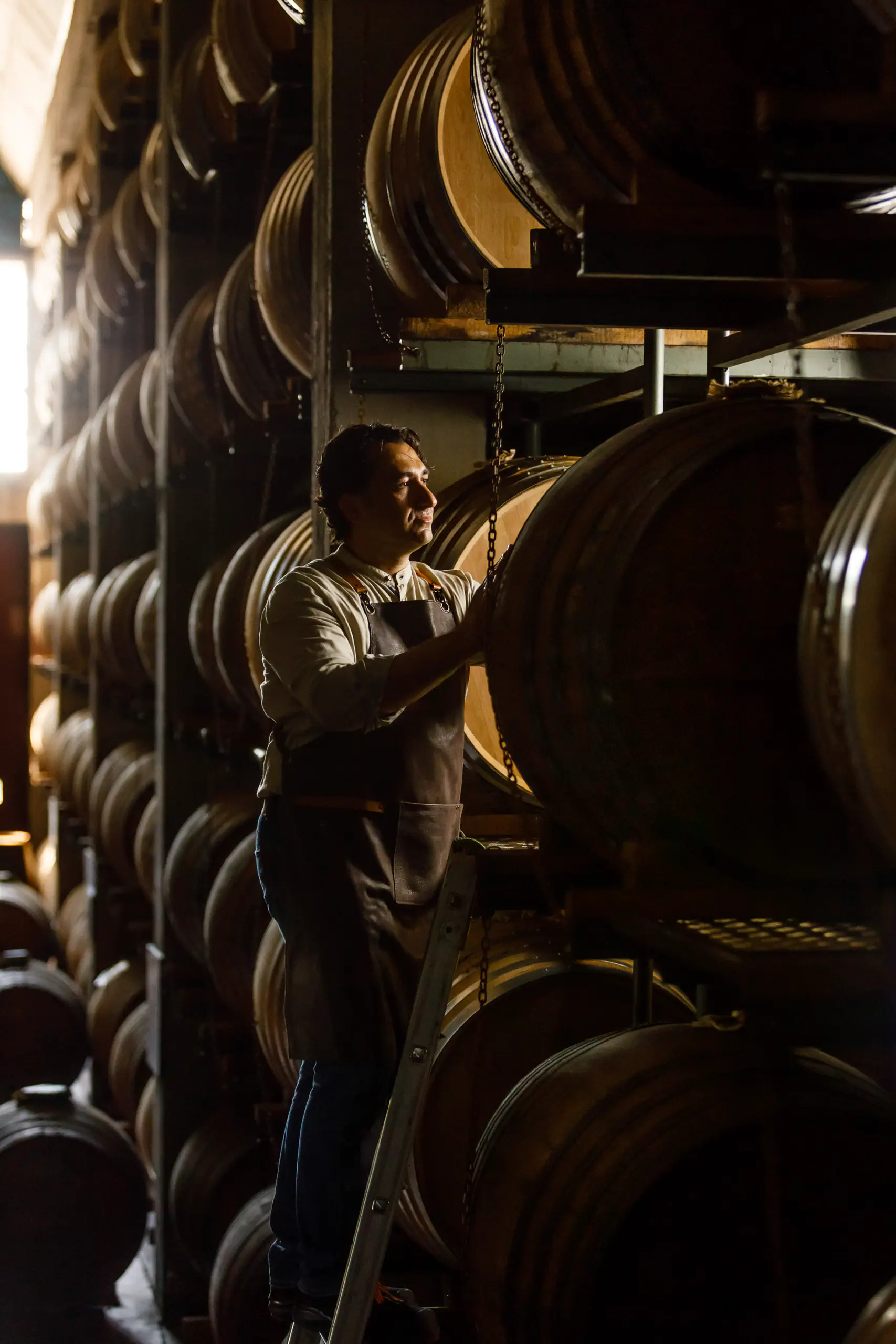 Man among stacked wine barrels in a cellar