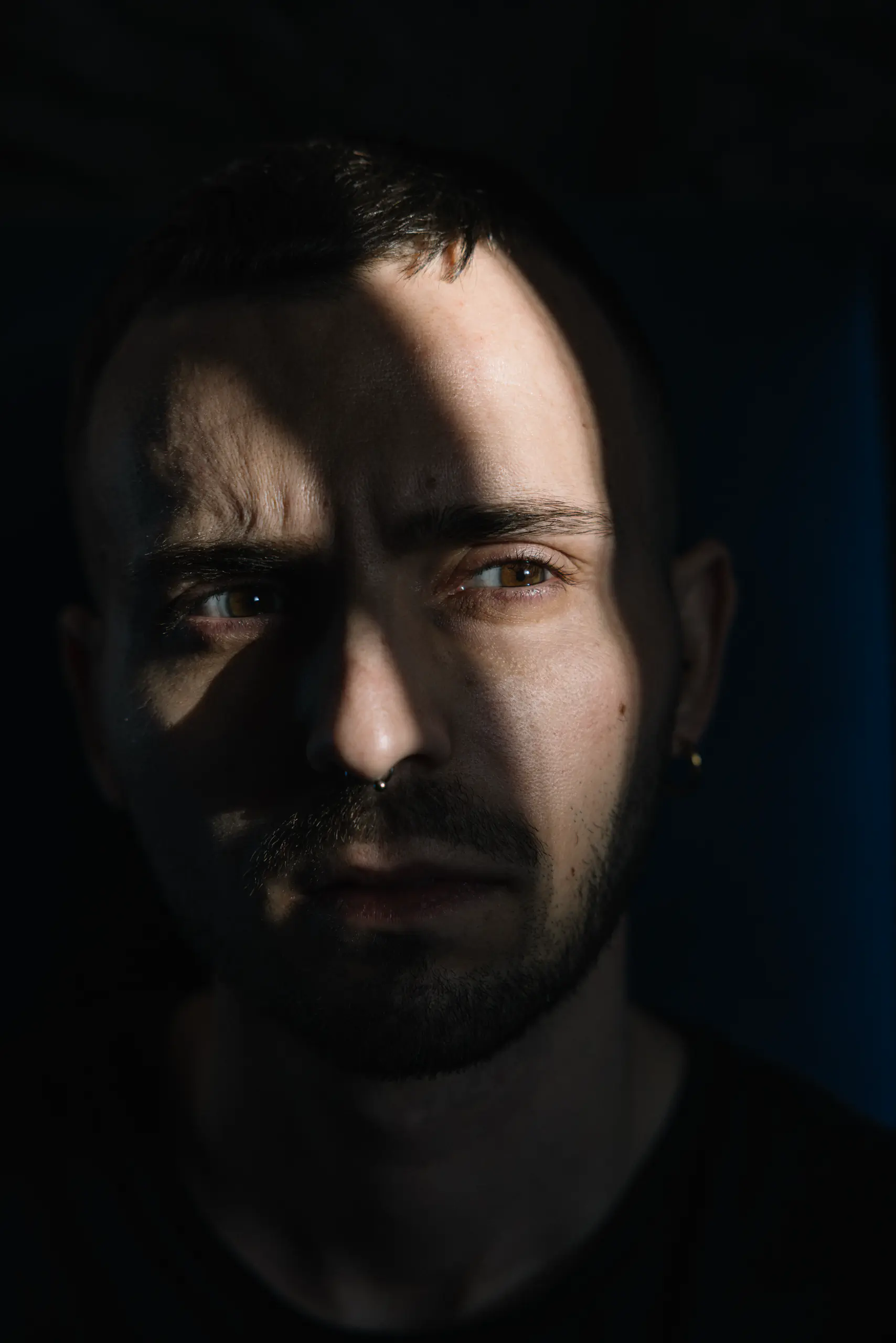Dramatic dark portrait of a man's face, half in shadow