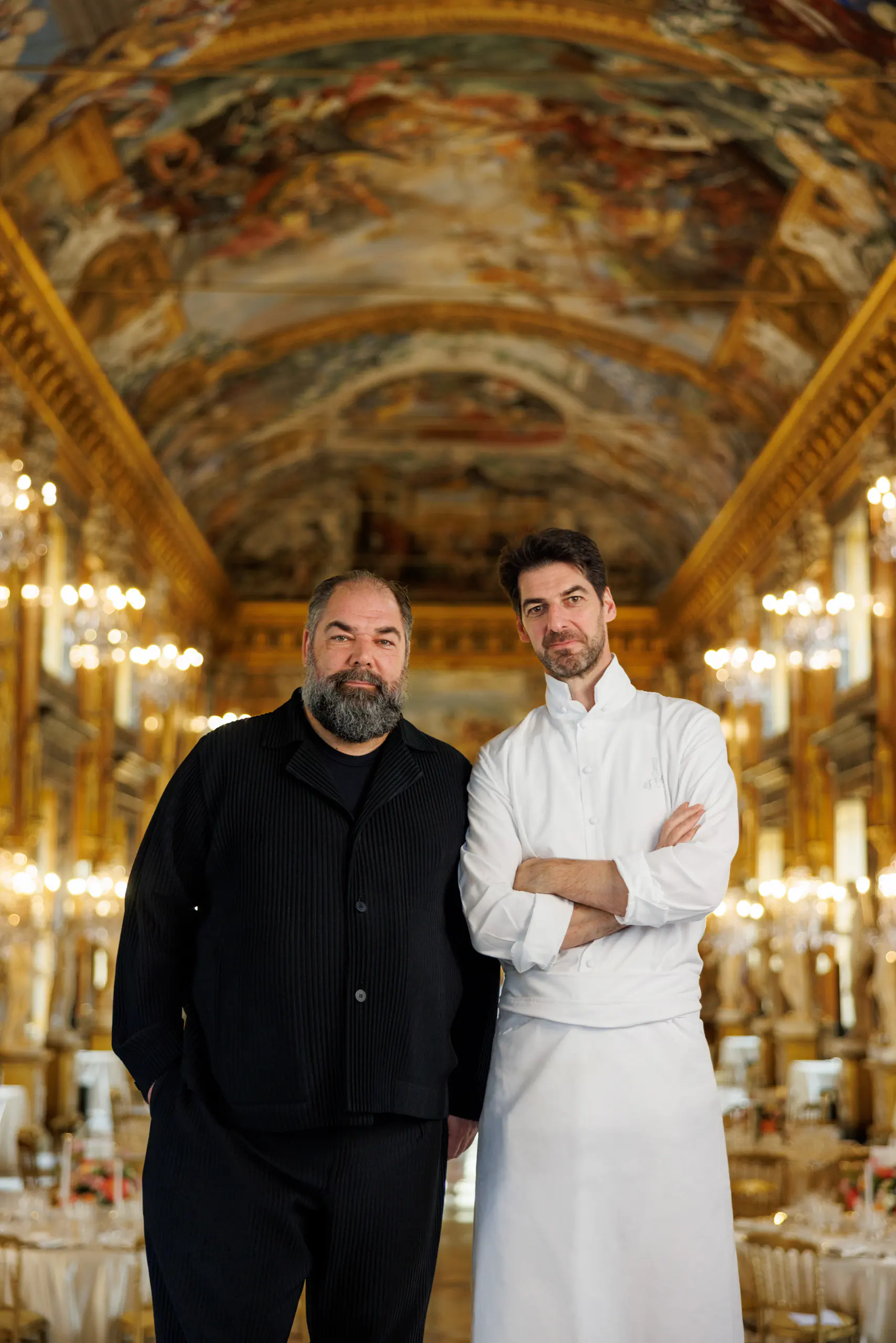 Two men posing in an ornate frescoed gilded hall