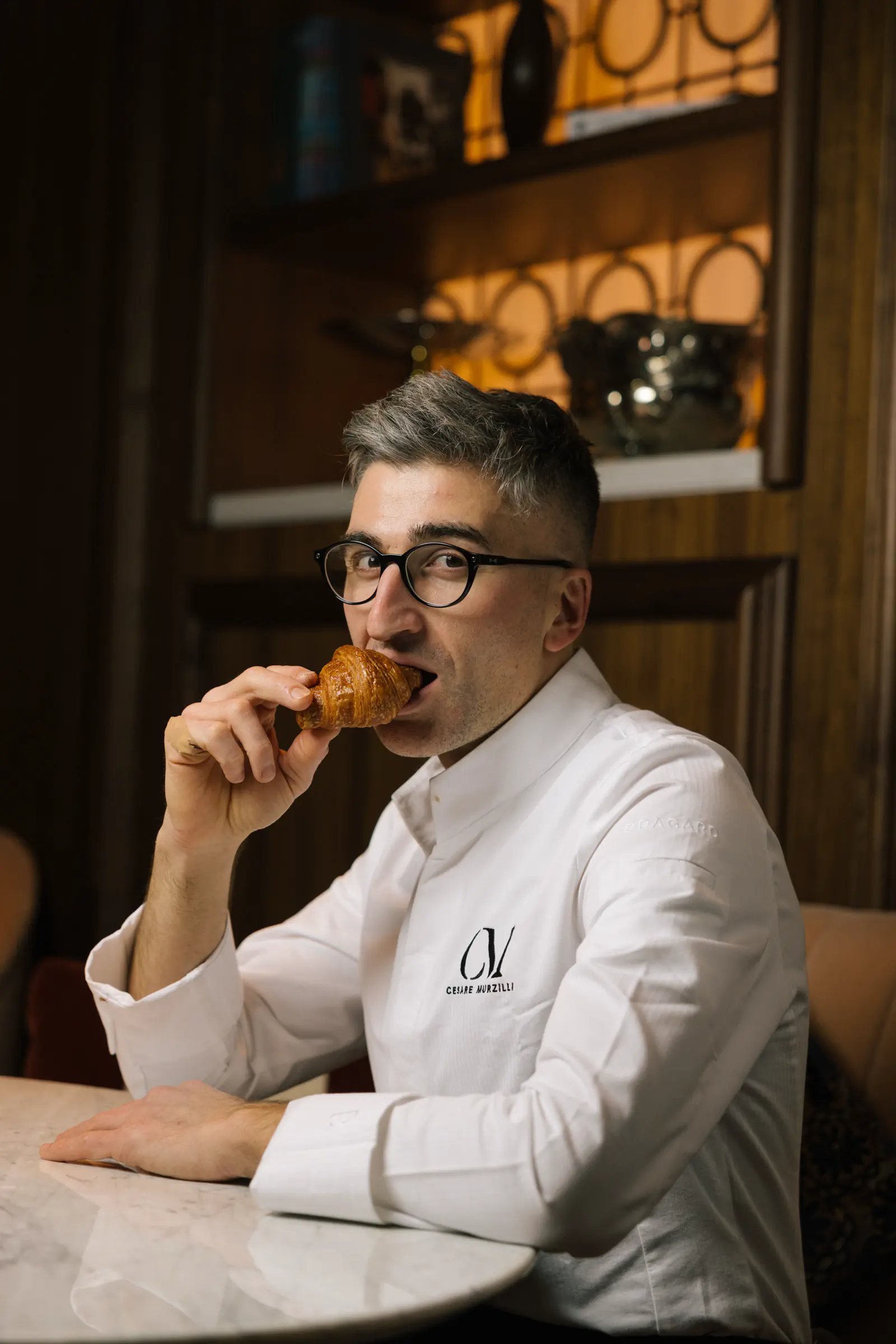 Chef in whites tasting from a spoon in a warm restaurant