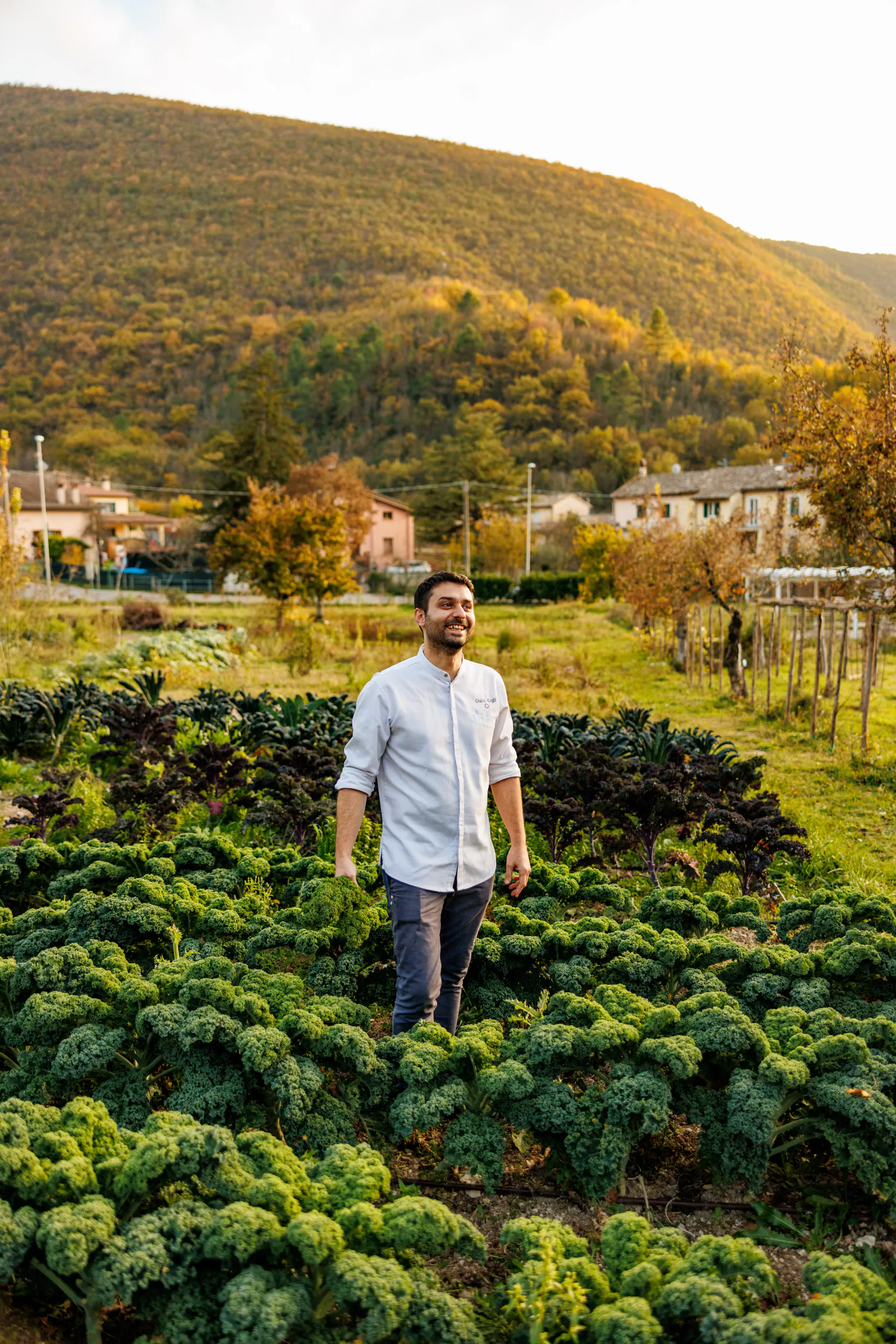 Man standing in a vegetable garden with hills behind
