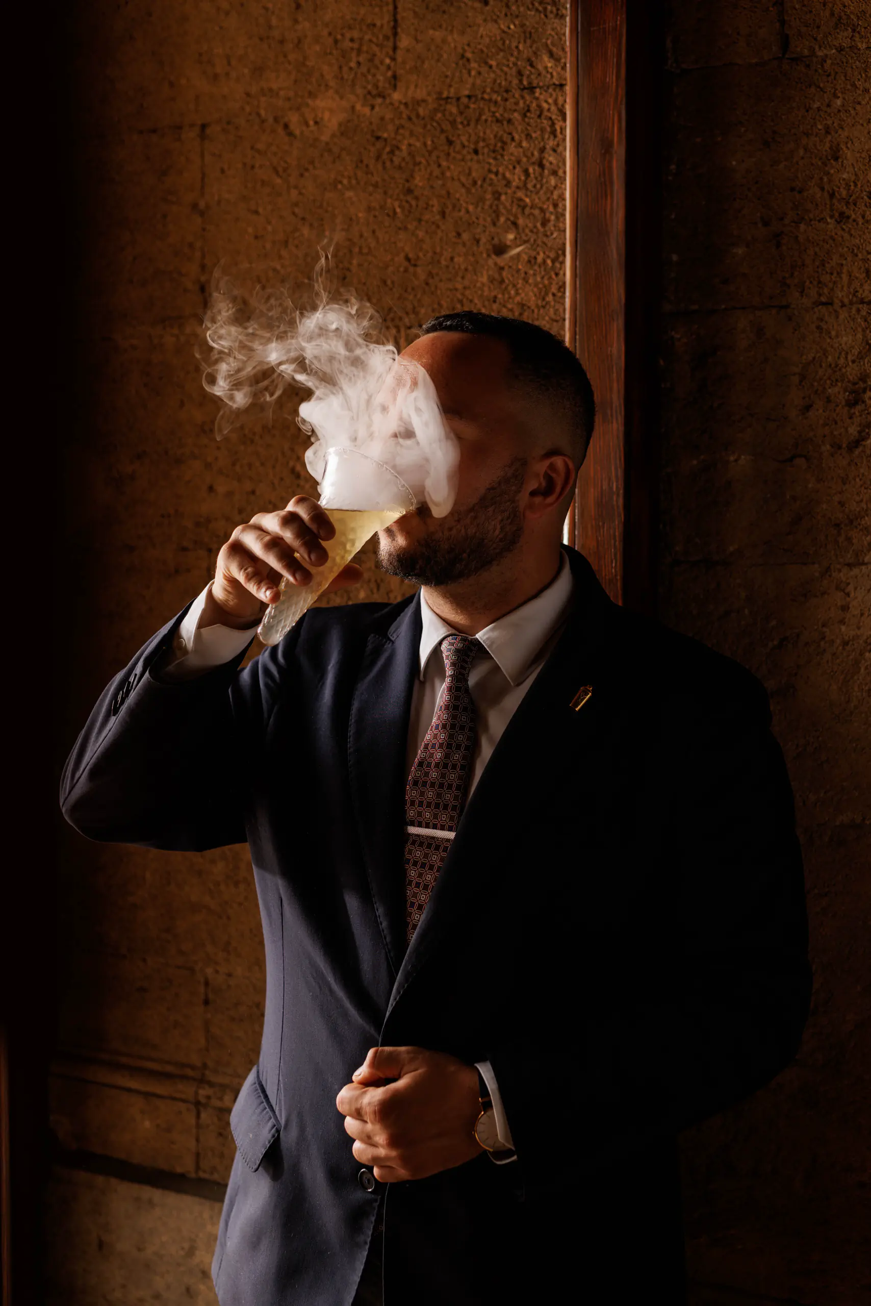 Man in a suit drinking from a glass in dramatic side light