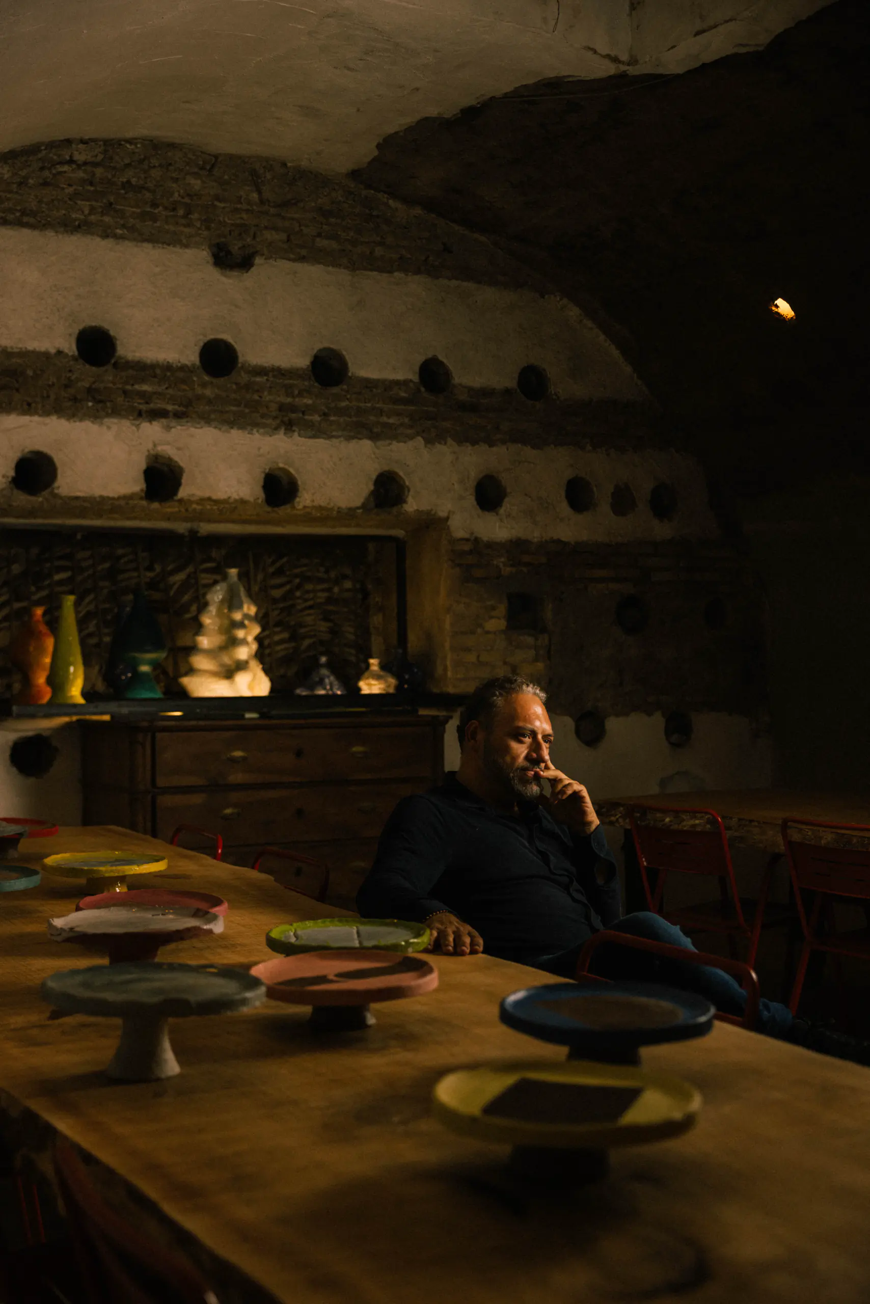 Man seated at a long table in a grand rustic hall with a brick vaulted ceiling