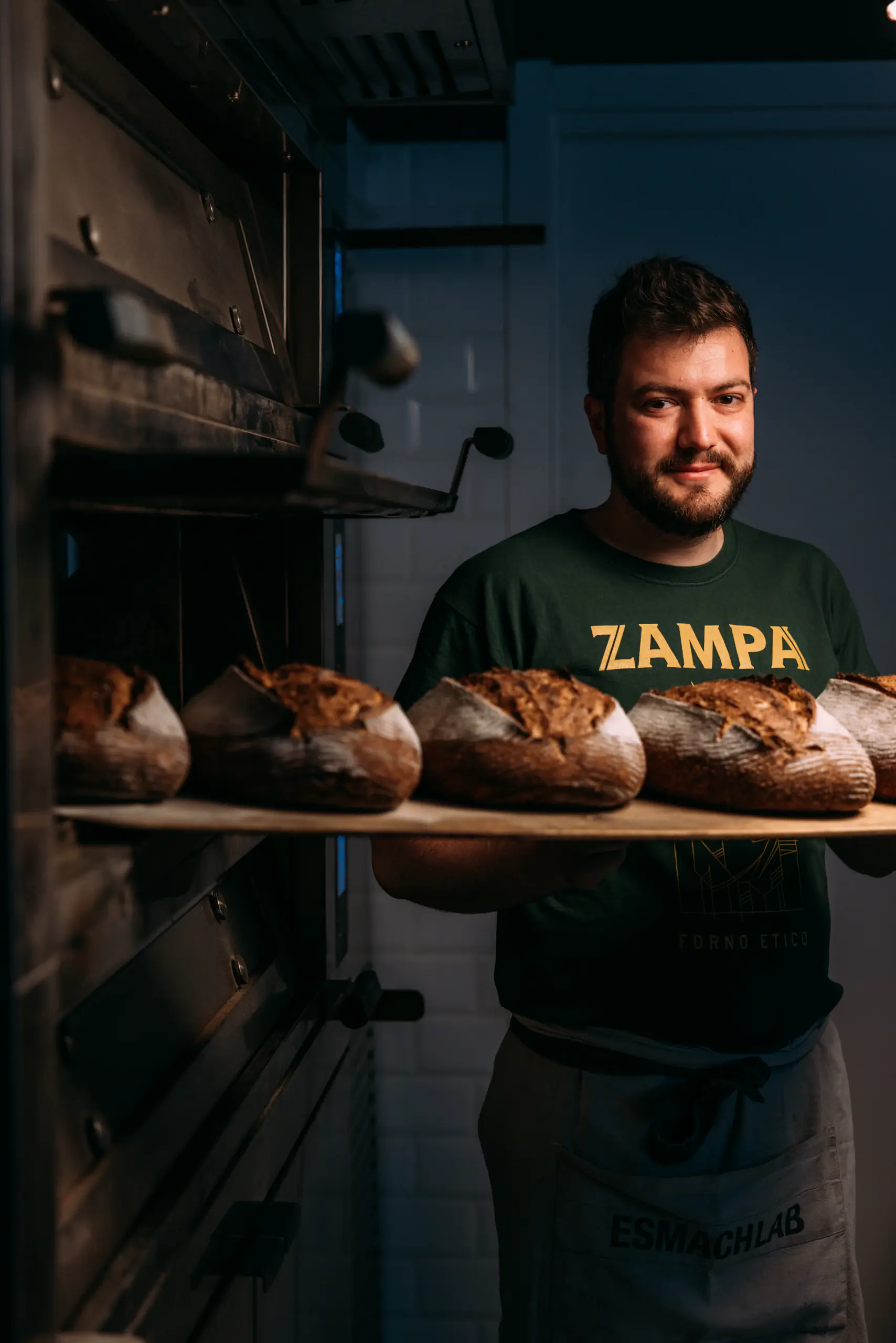 Man holding a tray of fresh bread in a bakery