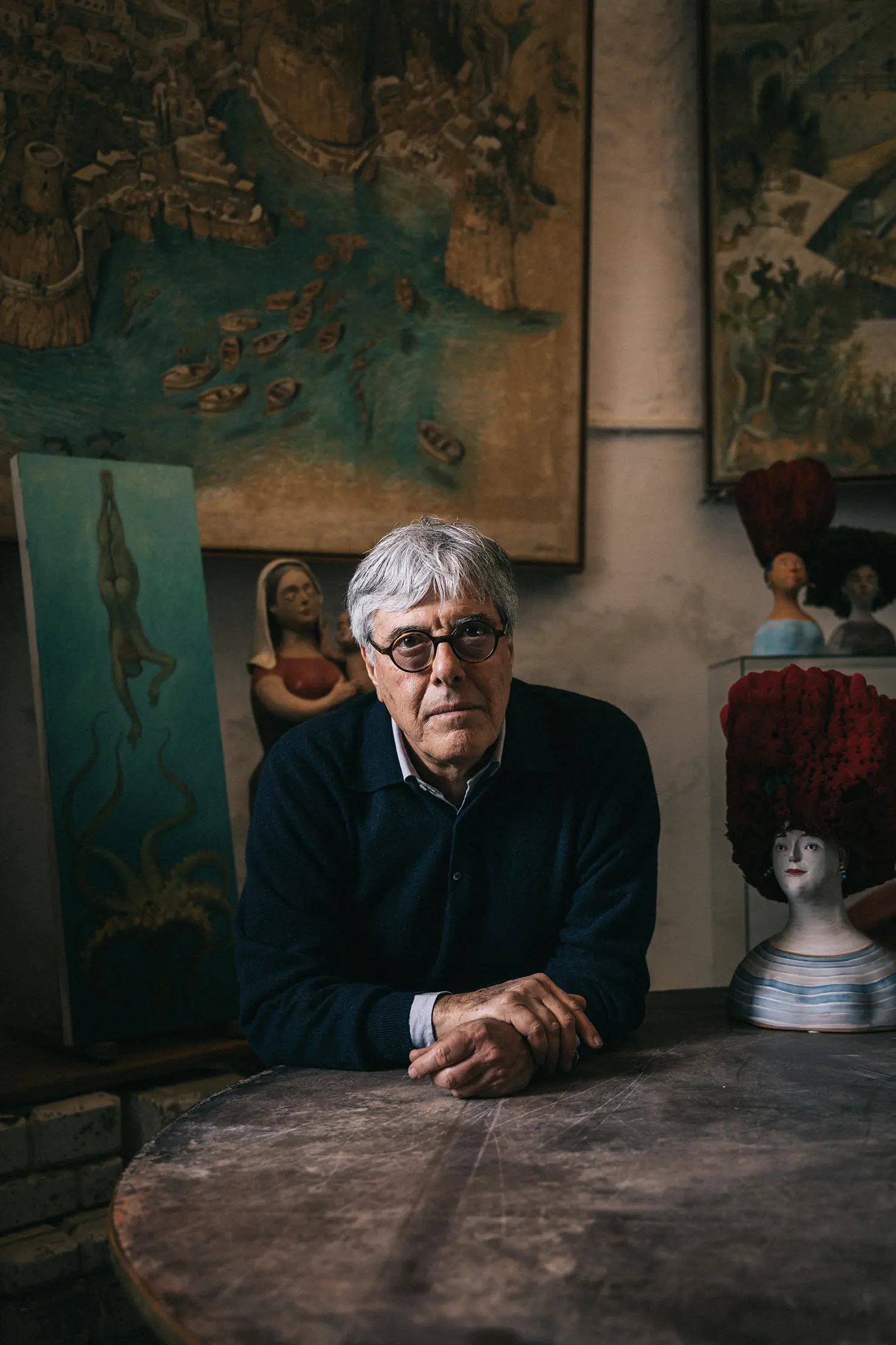 Older man seated at a table in a dimly lit room with antiques