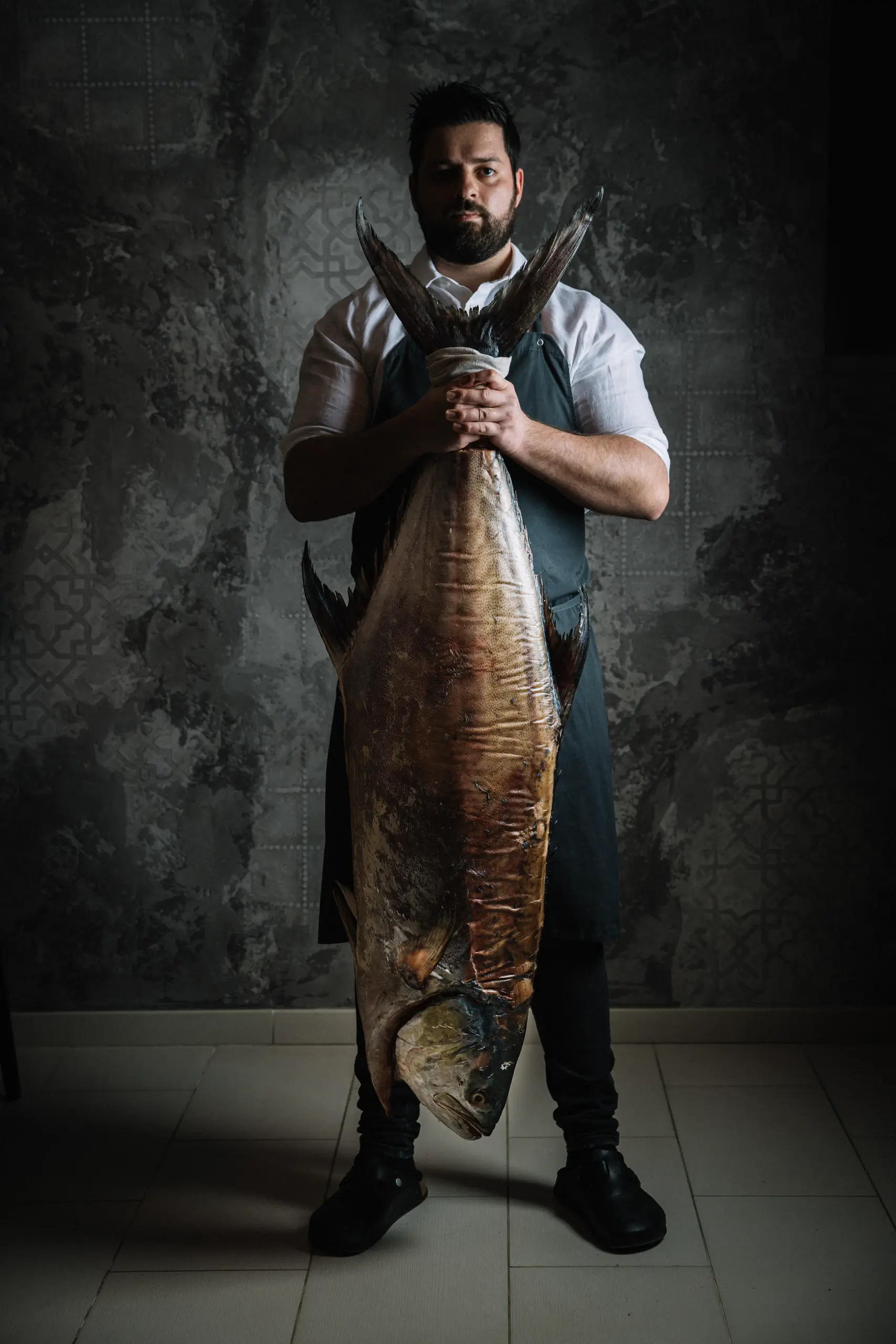 Man holding a large flatfish against a textured backdrop